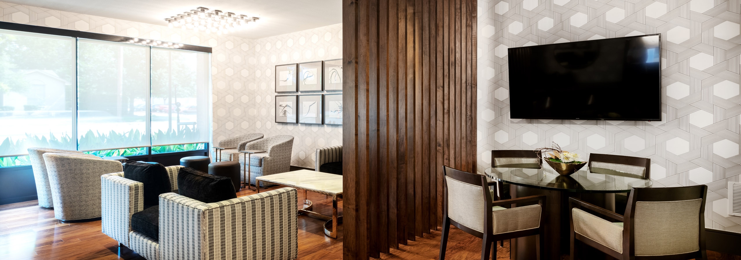Interior view of AMLI Grapevine resident clubroom with hardwood floor and multiple seating areas and a large screen TV