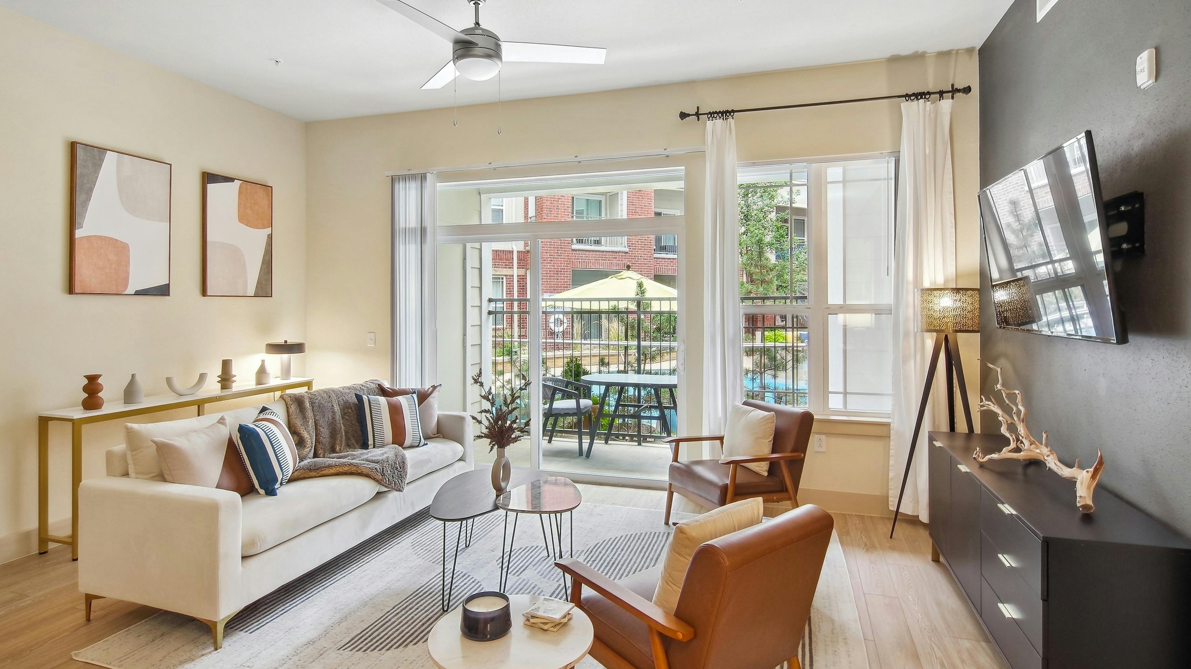 AMLI Park Avenue living room with a large area rug and a couch and 2 chairs as well as a TV and view to the pool