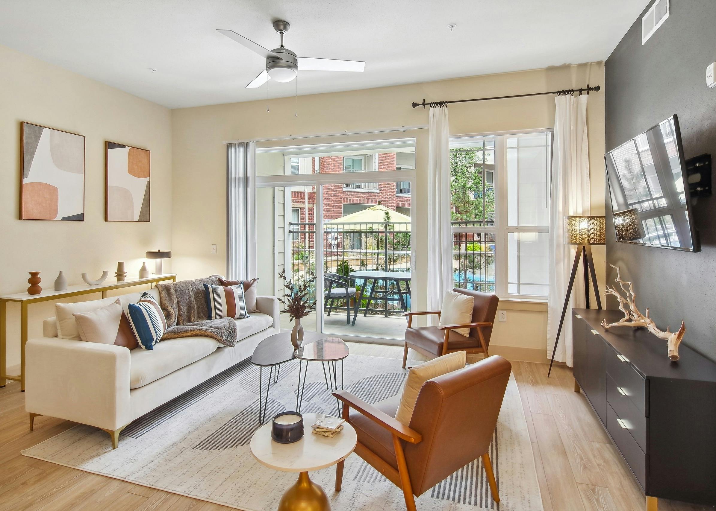 AMLI Park Avenue living room with a large area rug and a couch and 2 chairs as well as a TV and view to the pool