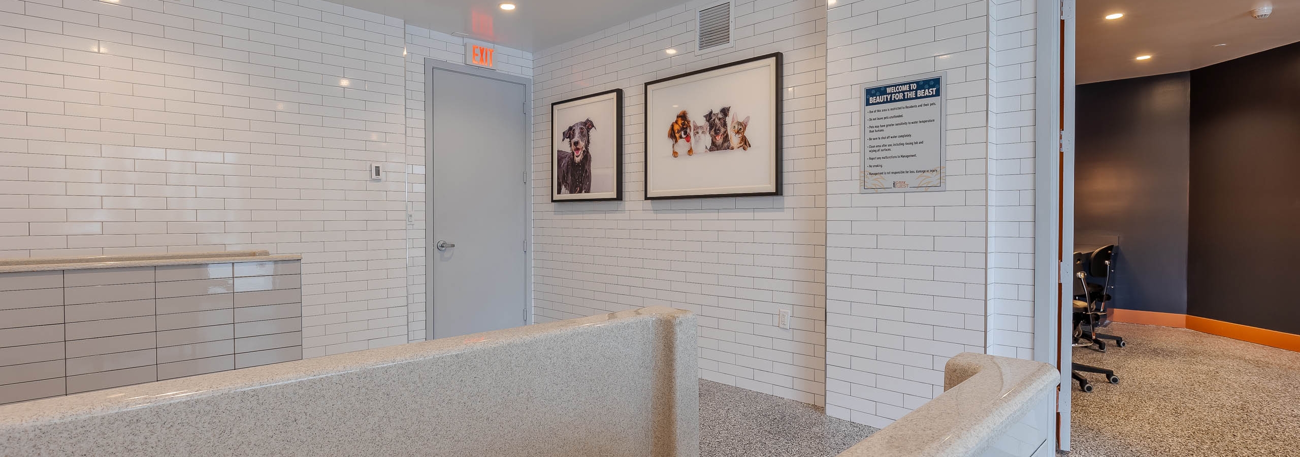 The AMLI Park West apartments pet spa with white subway tile walls and grooming tub with pet artwork on the wall