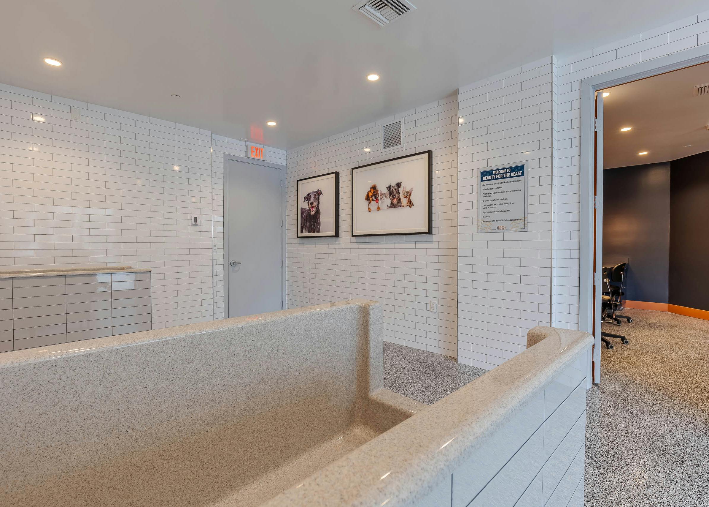 The AMLI Park West apartments pet spa with white subway tile walls and grooming tub with pet artwork on the wall