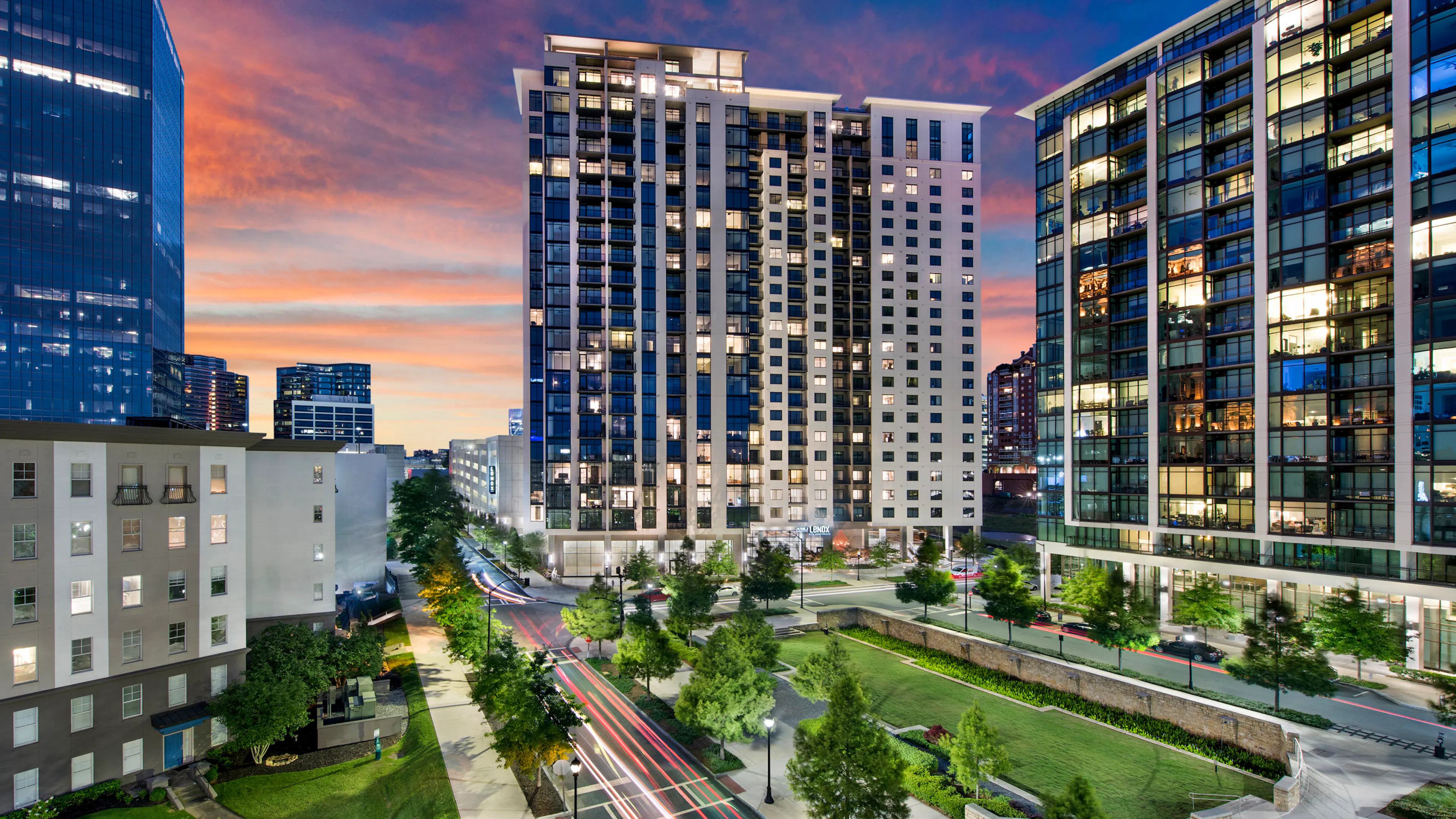 Nighttime exterior view of AMLI Lenox apartment building with brightly lit apartments overlooking Marie Simms Park