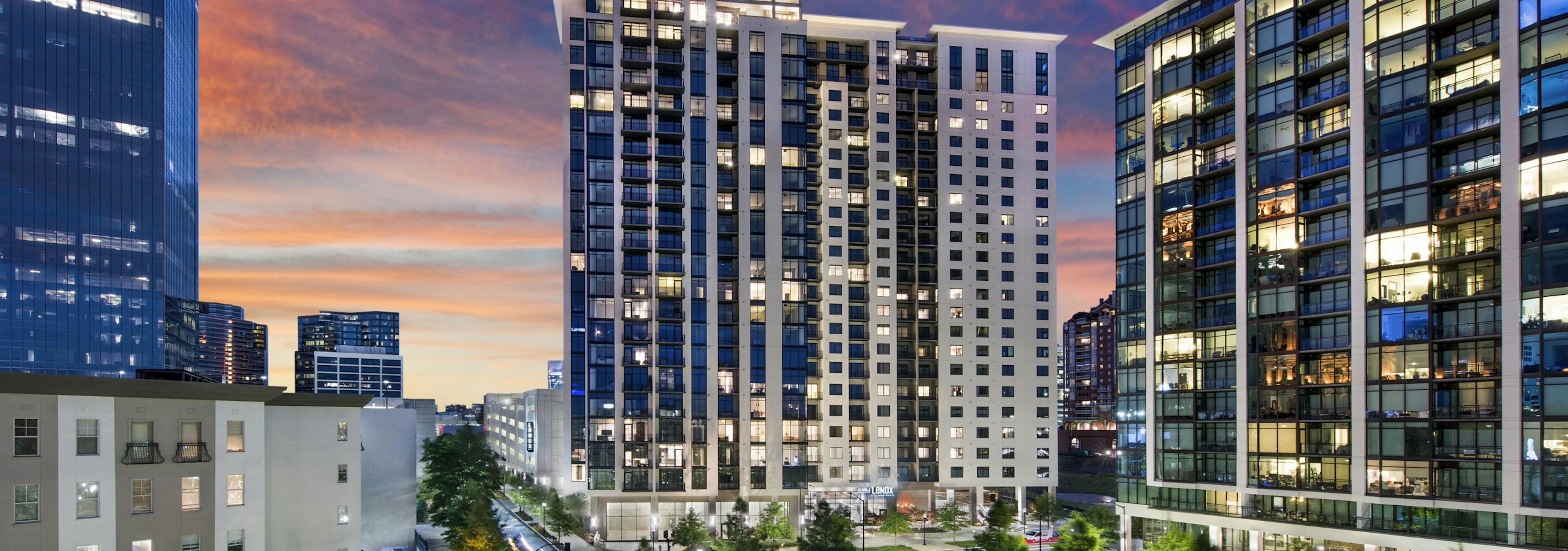 Nighttime exterior view of AMLI Lenox apartment building with brightly lit apartments overlooking Marie Simms Park