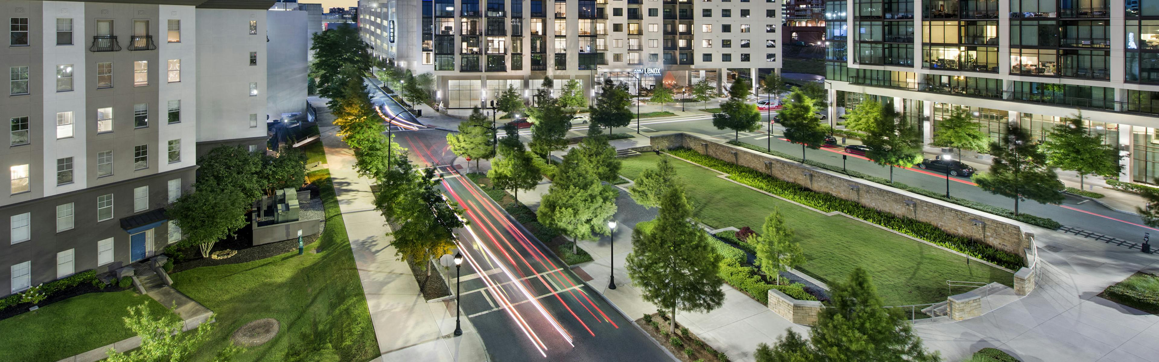 Nighttime exterior view of AMLI Lenox apartment building with brightly lit apartments overlooking Marie Simms Park