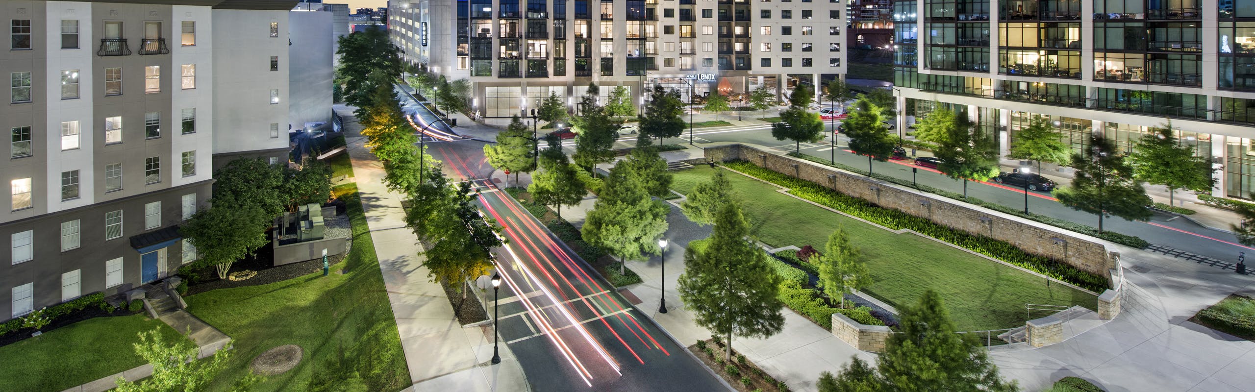 Nighttime exterior view of AMLI Lenox apartment building with brightly lit apartments overlooking Marie Simms Park