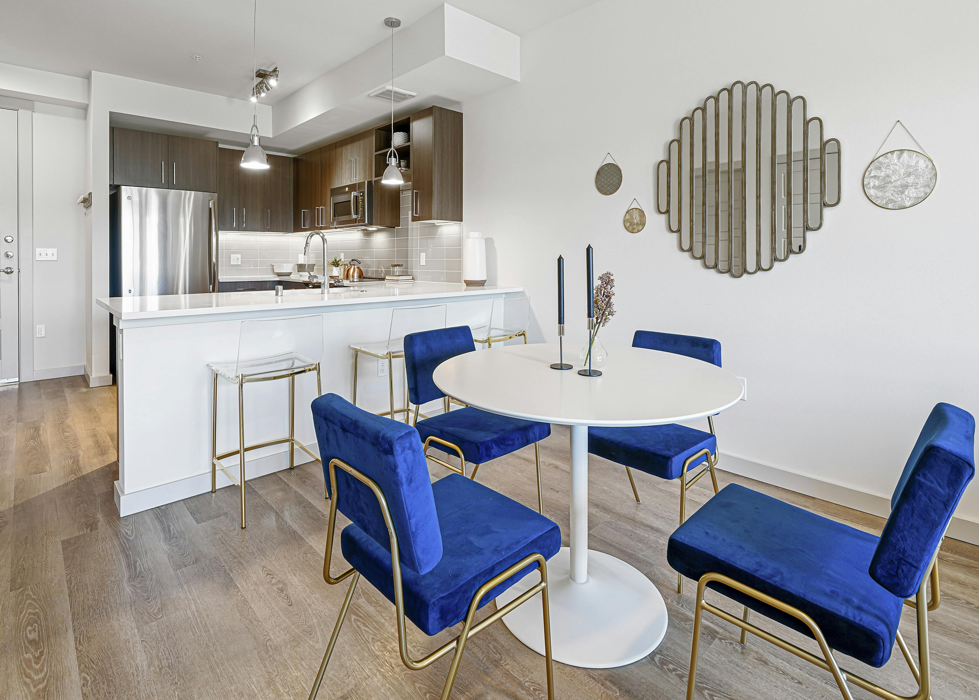 AMLI Spring District apartment kitchen with brown cabinets and dining room with white table and four blue chairs 