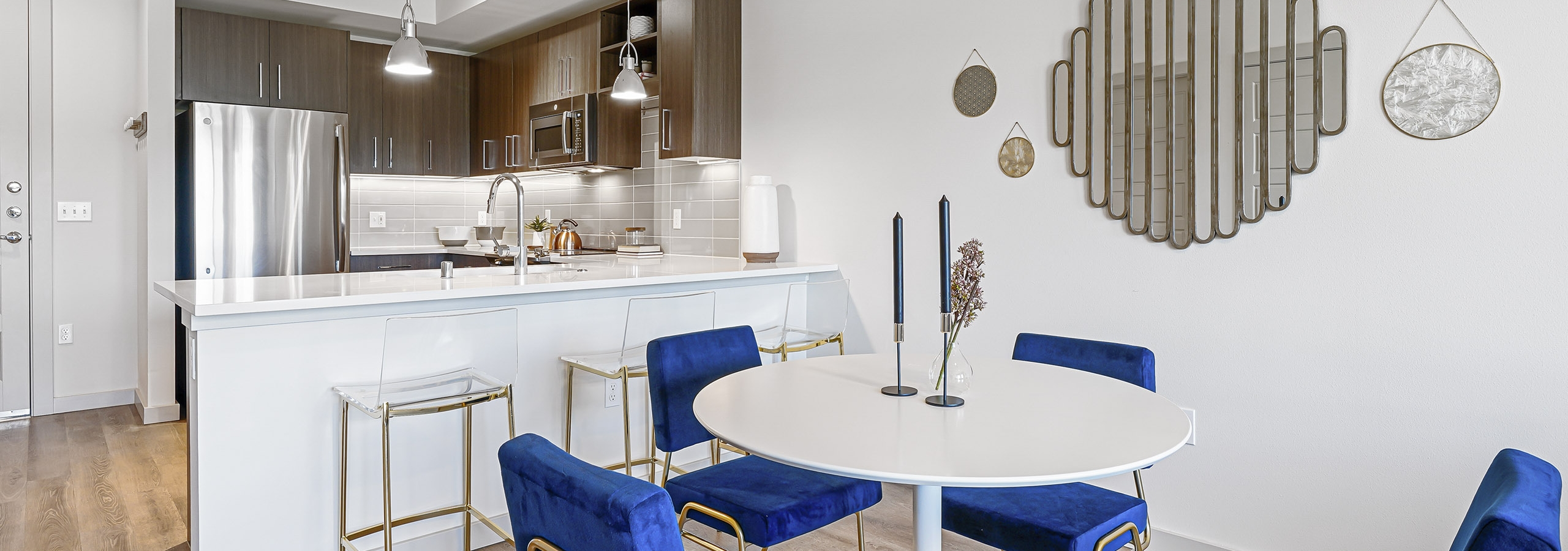 AMLI Spring District apartment kitchen with brown cabinets and dining room with white table and four blue chairs