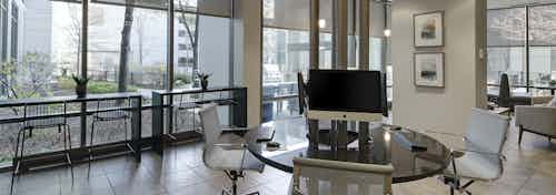 Business center at AMLI 900 with circular workstation and 4 computers and other tables and chairs by 2 walls of windows