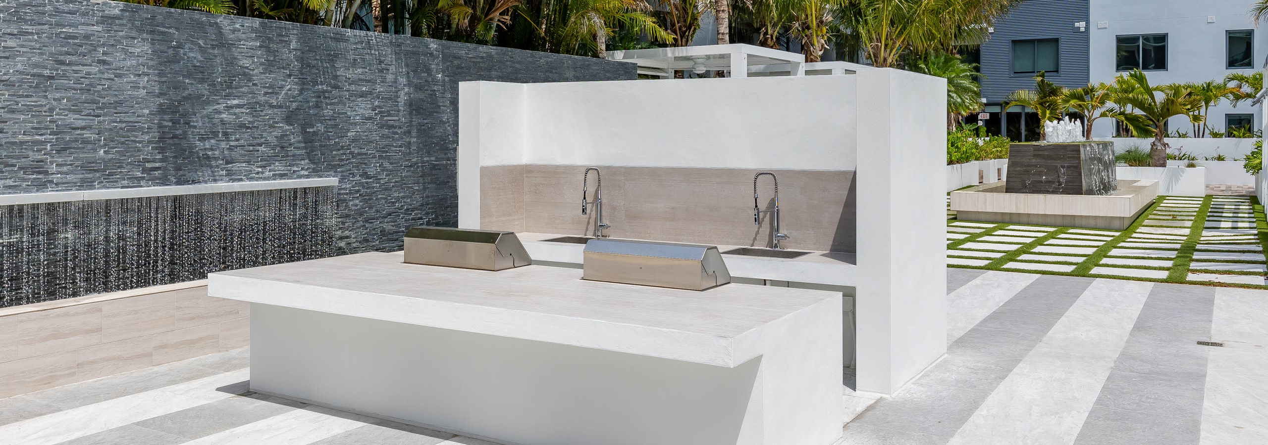 AMLI Midtown Miami apartments grill station with stainless steel grills and cascading water fountains with palm trees