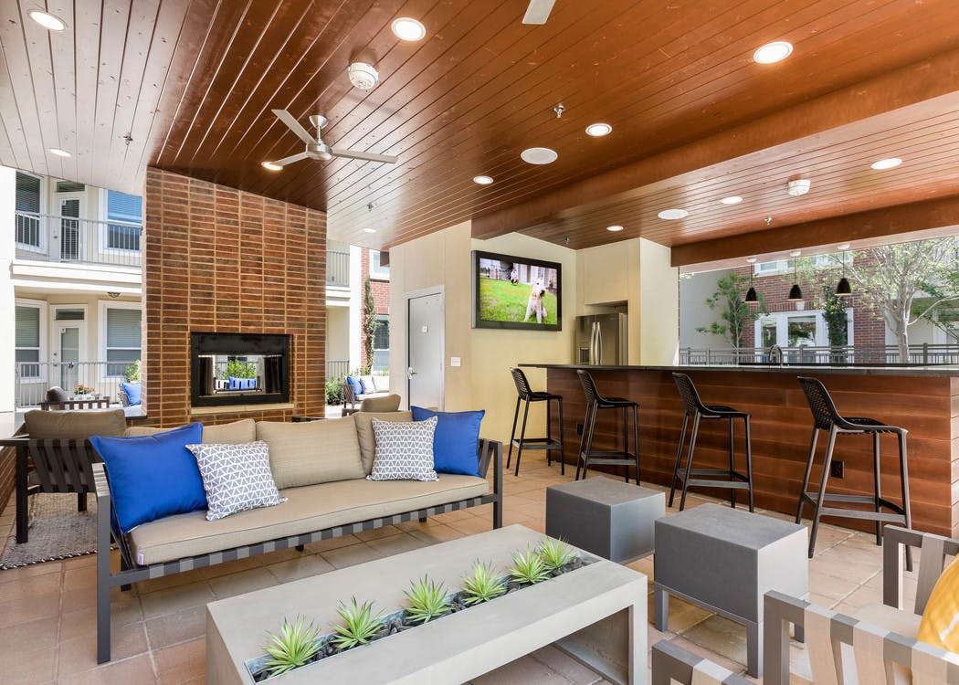 Daytime view of cabana at AMLI Frisco Crossing apartments with serving bar and big screen TV and seating and fireplace