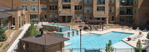 Ariel view of pool at AMLI Inverness apartments with a waterfall feature and surrounding lounge chairs and view of balconies