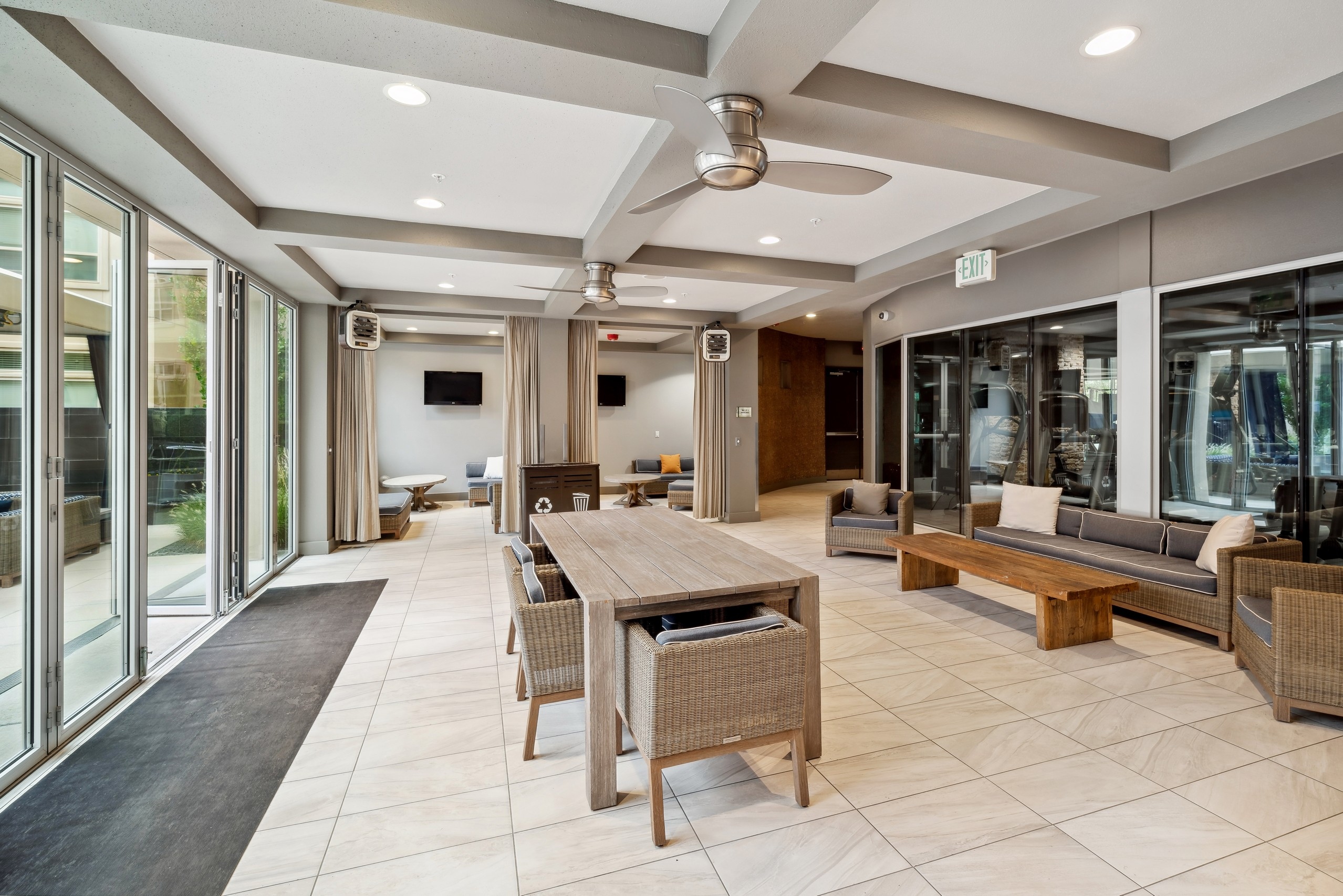 A resident lounge at AMLI RidgeGate with two cabana spaces with televisions and couches with coffee tables and curtains