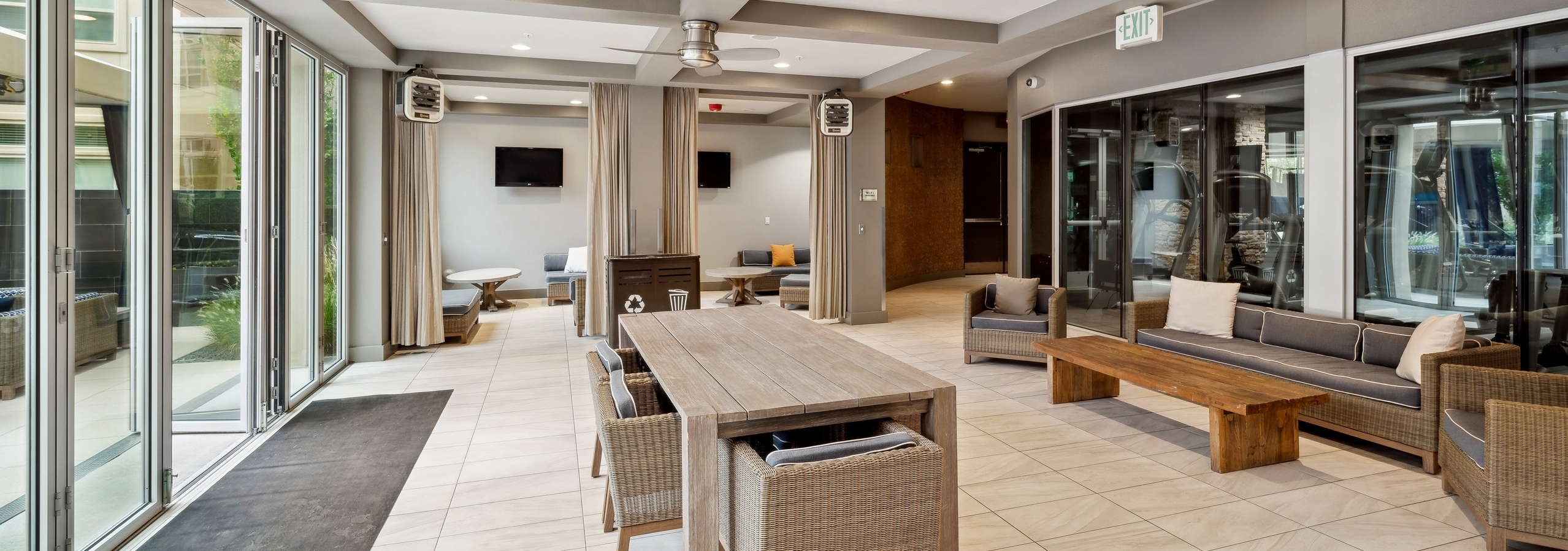 A resident lounge at AMLI RidgeGate with two cabana spaces with televisions and couches with coffee tables and curtains