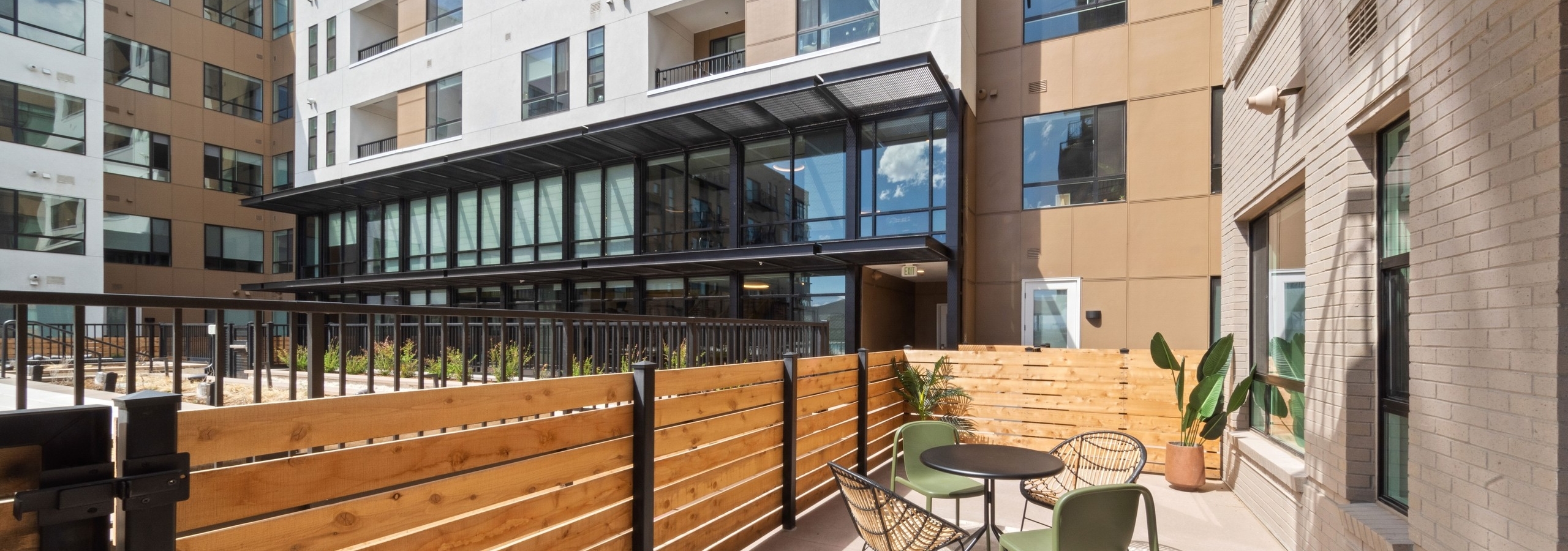 Exterior view of an apartment patio at AMLI Broadway Park featuring a natural wood fence and a small dining table with chairs