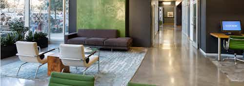 Alternate seating area in the AMLI on 2nd leasing office with peek down hallway and dark grey walls with a desk and computer
