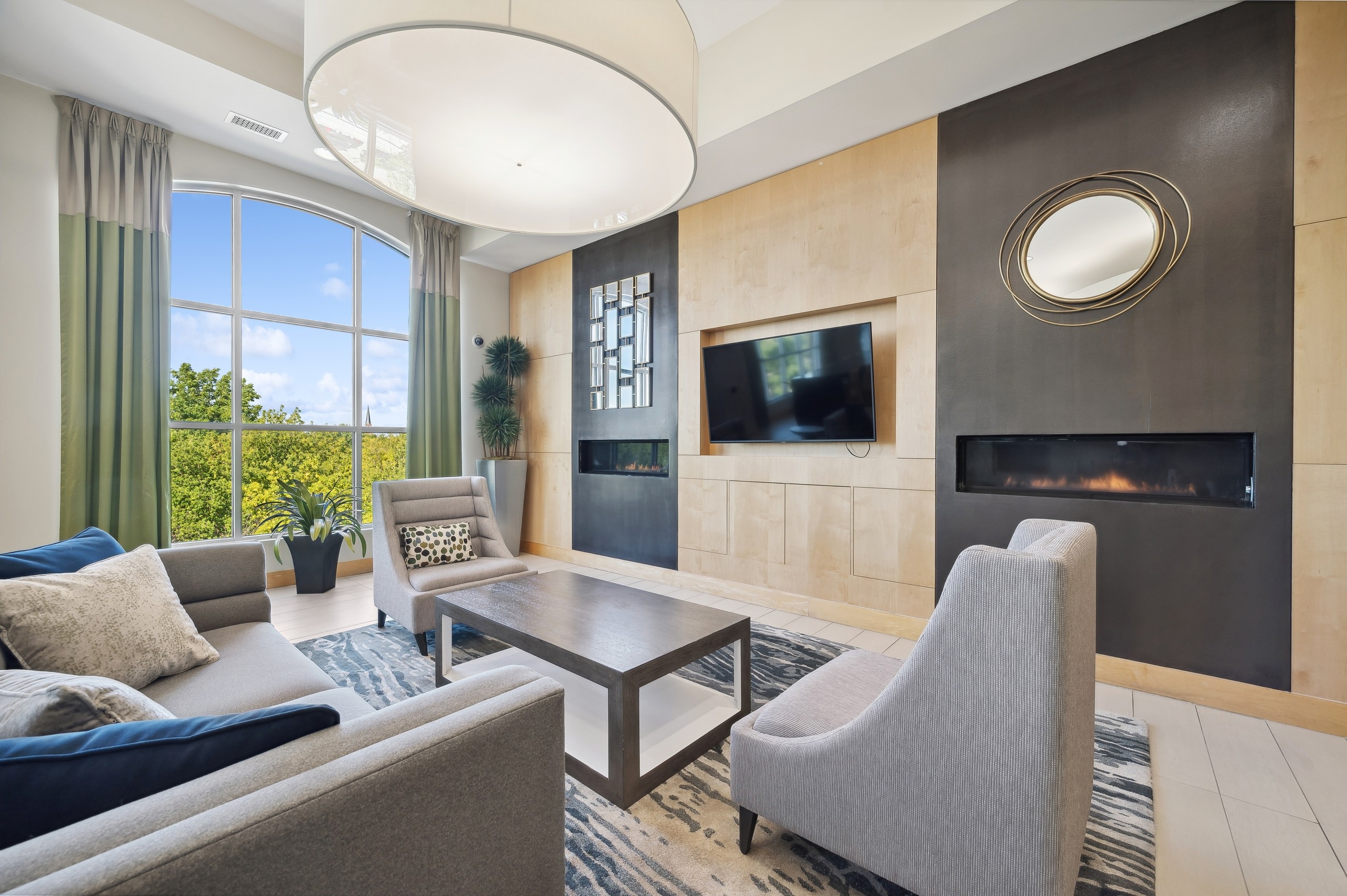 Couch and 2 chairs around coffee table and facing TV and two fireplaces near a large window at AMLI Evanston