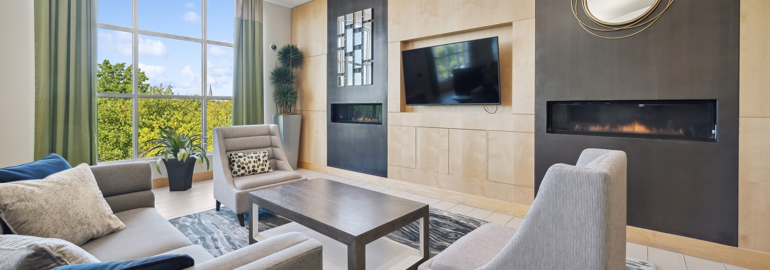 Couch and 2 chairs around coffee table and facing TV and two fireplaces near a large window at AMLI Evanston