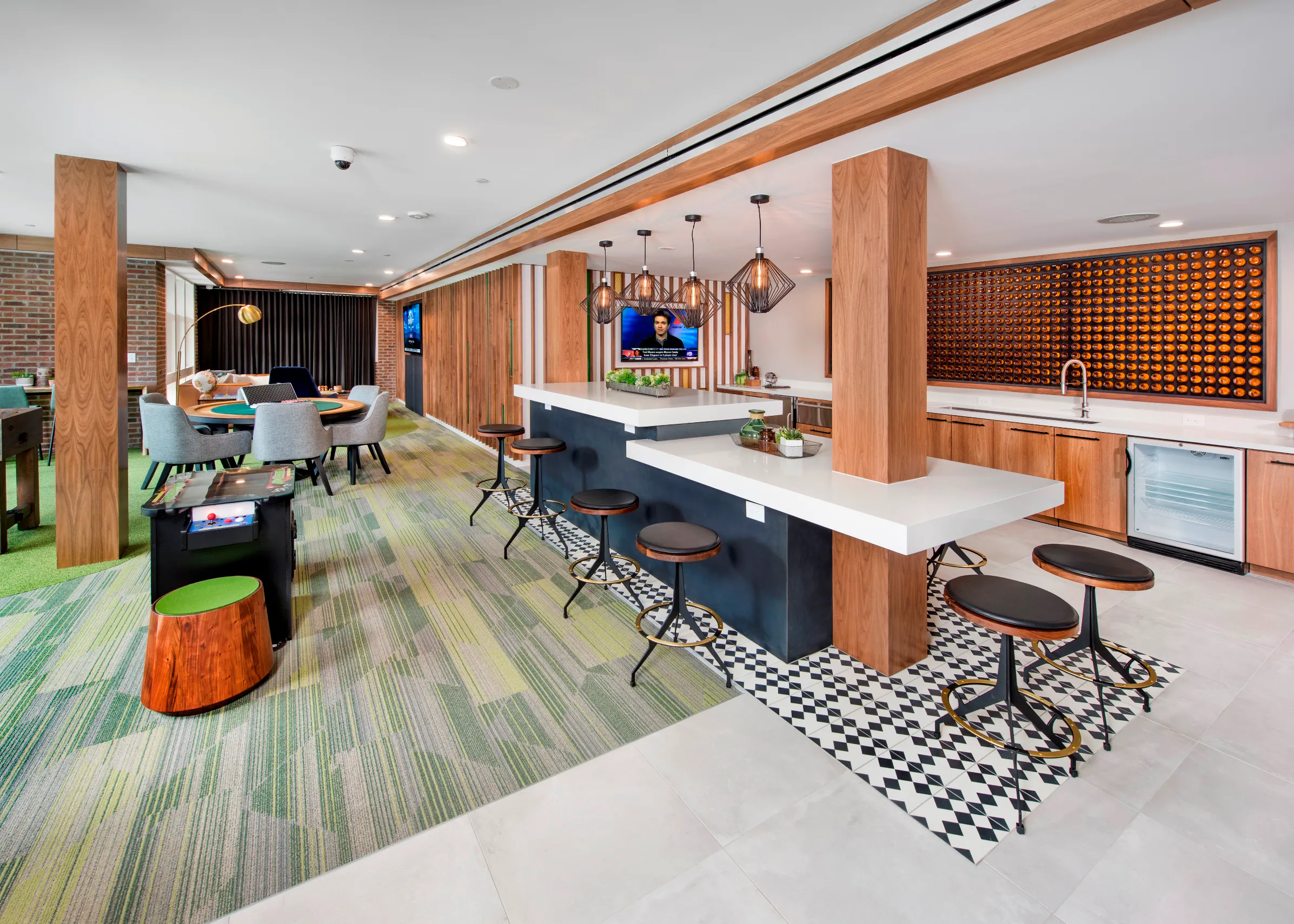 Interior view of club room at AMLI Decatur with serving kitchen, arcade game, poker table, big screen TV and green carpet