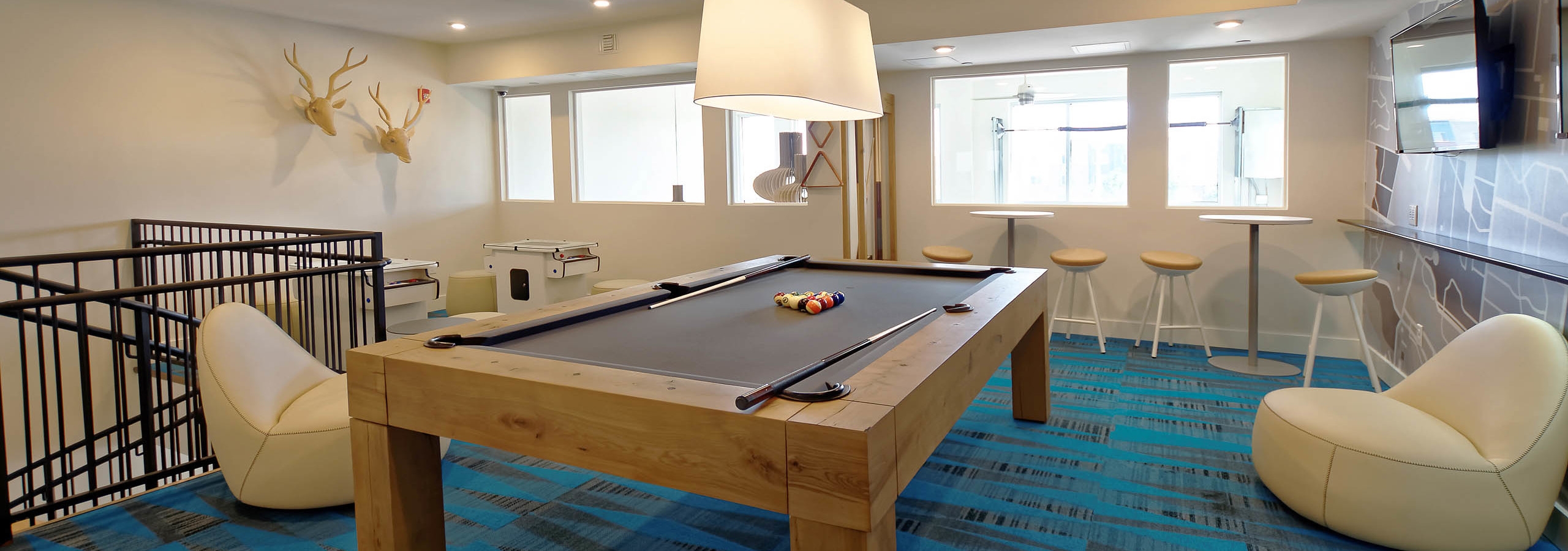 Interior view of a resident lounge at AMLI Dry Creek apartments with a dining table a kitchen area and a spiral staircase