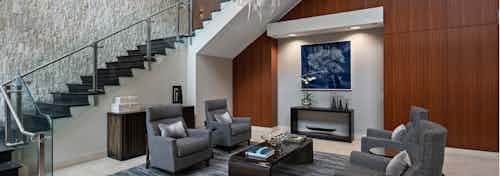 AMLI River North lobby with a cherry wood accent wall and grey seating in front of a modern wrap around staircase