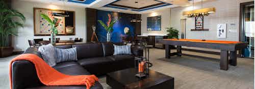 Interior game room at AMLI Doral with orange billiard table, large wall scrabble game, bright wall mural and seating area