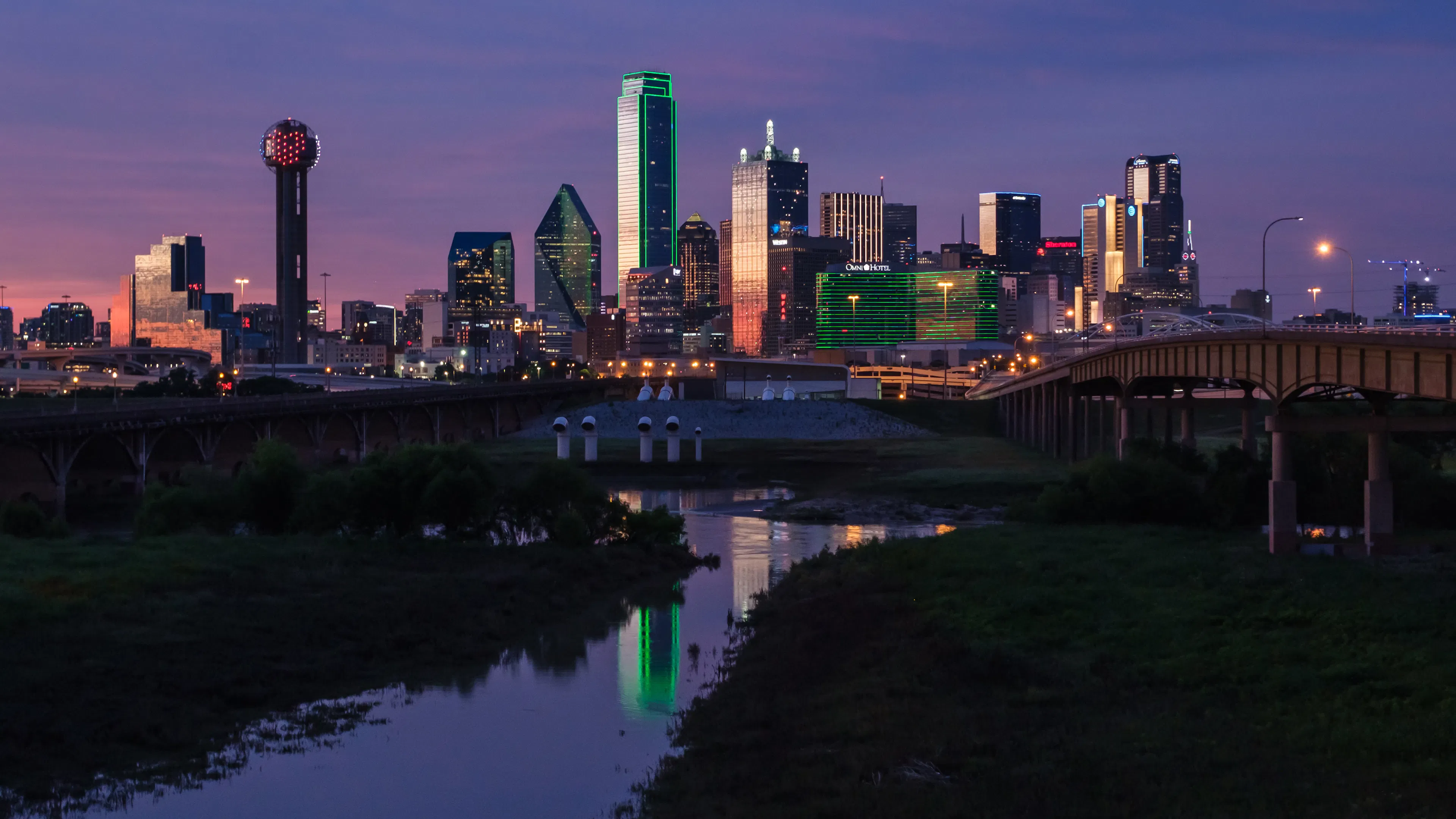The Dallas city skyline at night reflected in a river