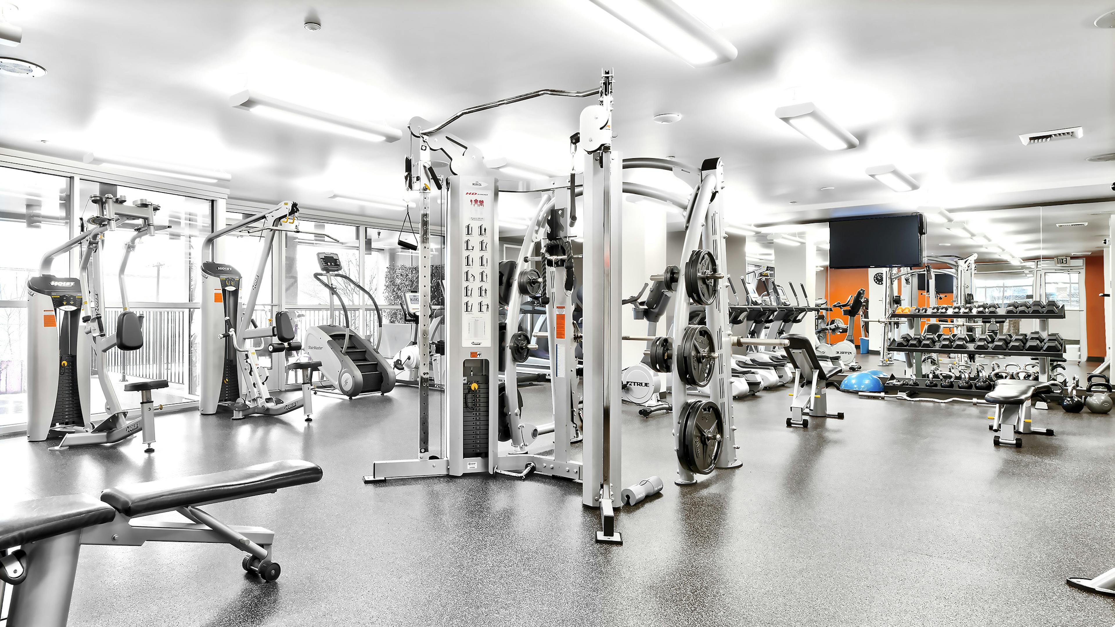 Interior view of the fitness center at AMLI Mark24 apartment building with weight machines and treadmills and free weights