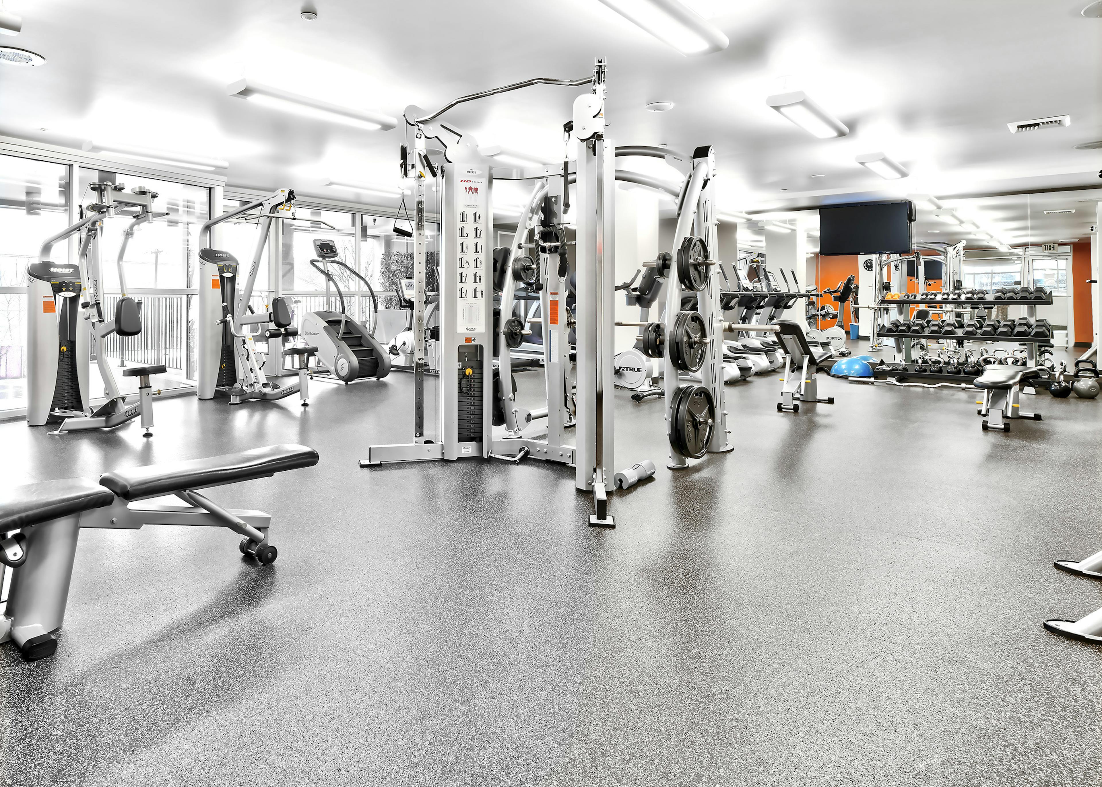 Interior view of the fitness center at AMLI Mark24 apartment building with weight machines and treadmills and free weights