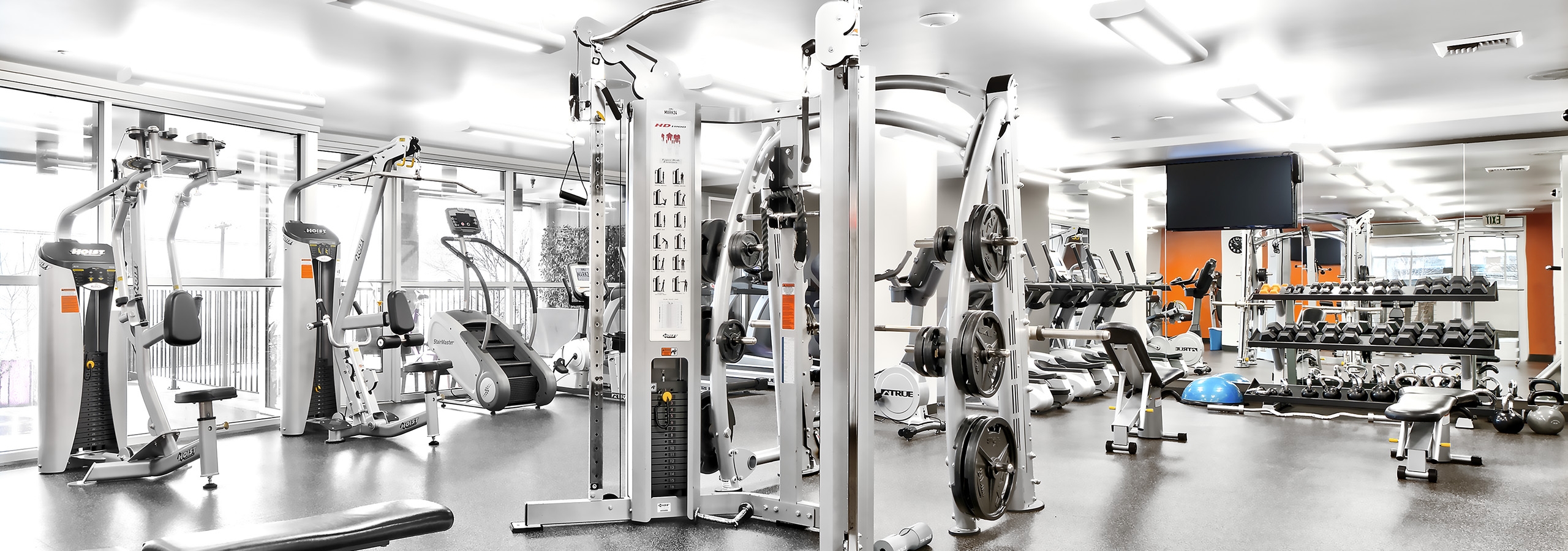 Interior view of the fitness center at AMLI Mark24 apartment building with weight machines and treadmills and free weights