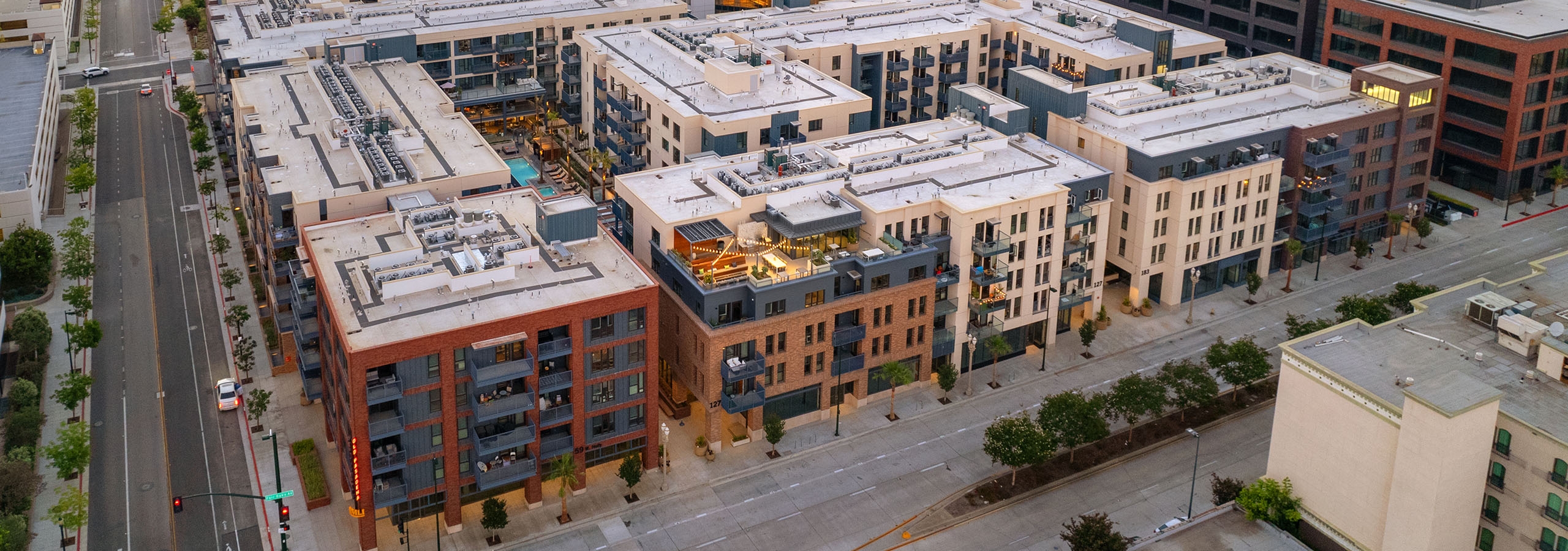 Aerial view at dusk of AMLI Old Pasadena apartment building showcasing a full background view of the mountains and the city