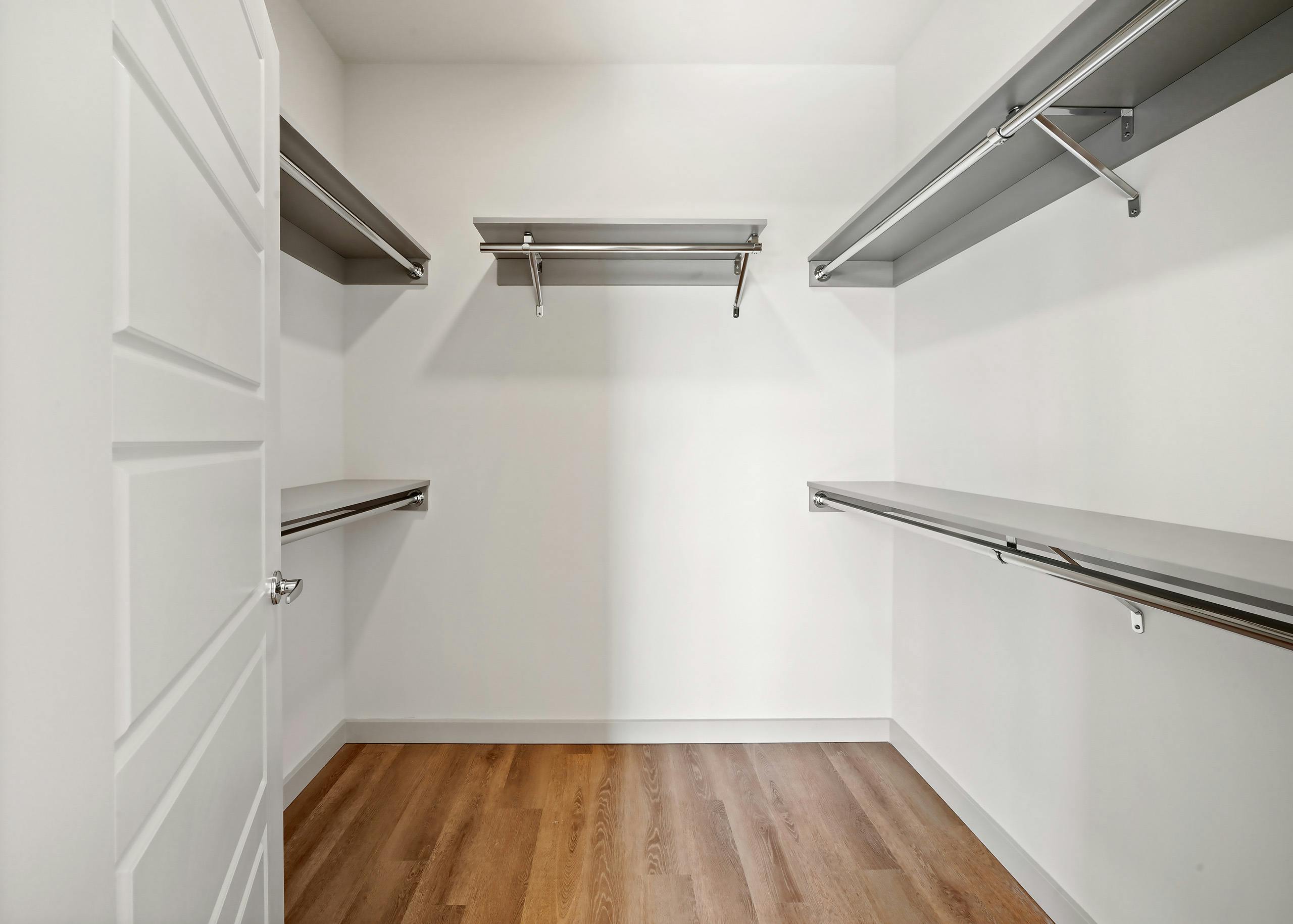 Interior view of a large California walk-in closet with five shelves and hanging poles at AMLI Spring District apartments