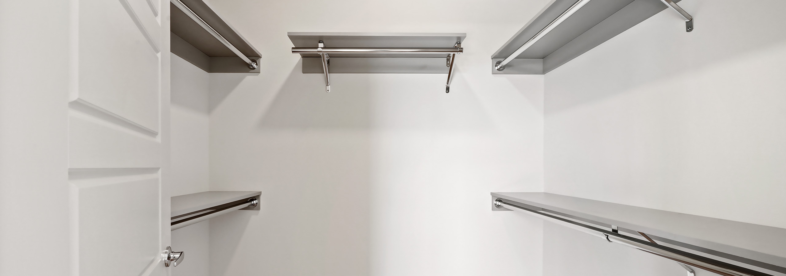 Interior view of a large California walk-in closet with five shelves and hanging poles at AMLI Spring District apartments