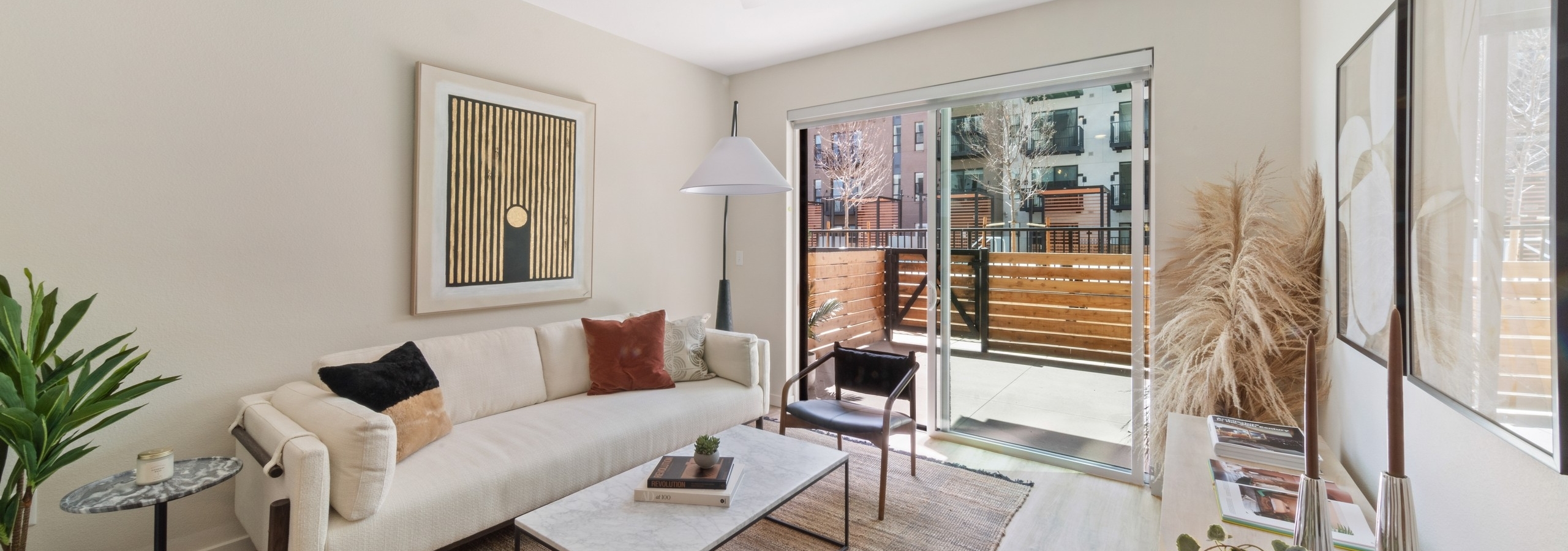 AMLI Broadway Park living room with a white couch and coffee table and a view out large sliding glass doors to the patio