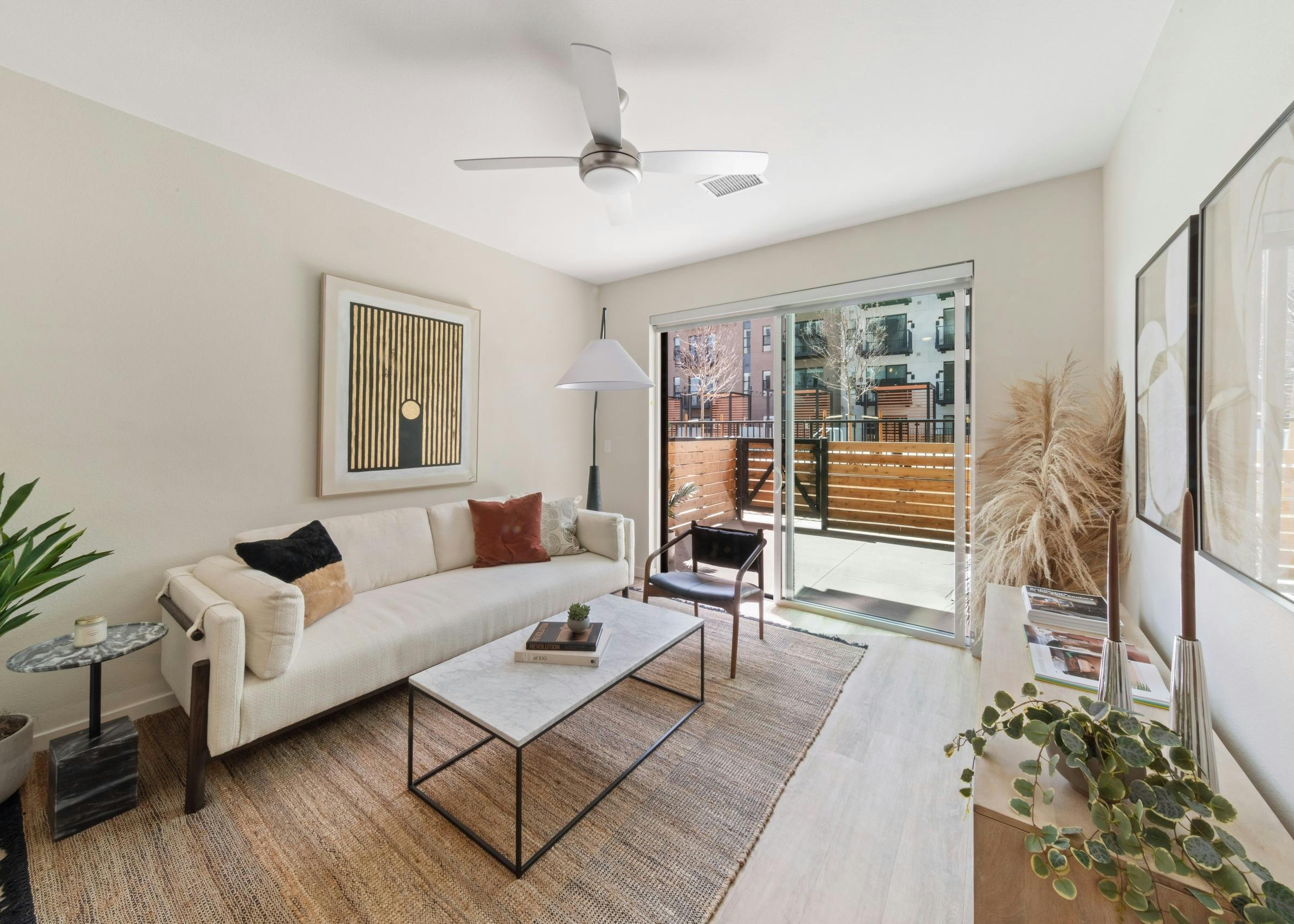 AMLI Broadway Park living room with a white couch and coffee table and a view out large sliding glass doors to the patio