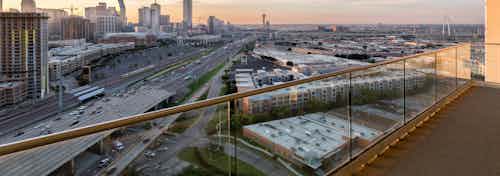 Dusk exterior view of AMLI Design District apartment building balcony with glass railing overlooking the city