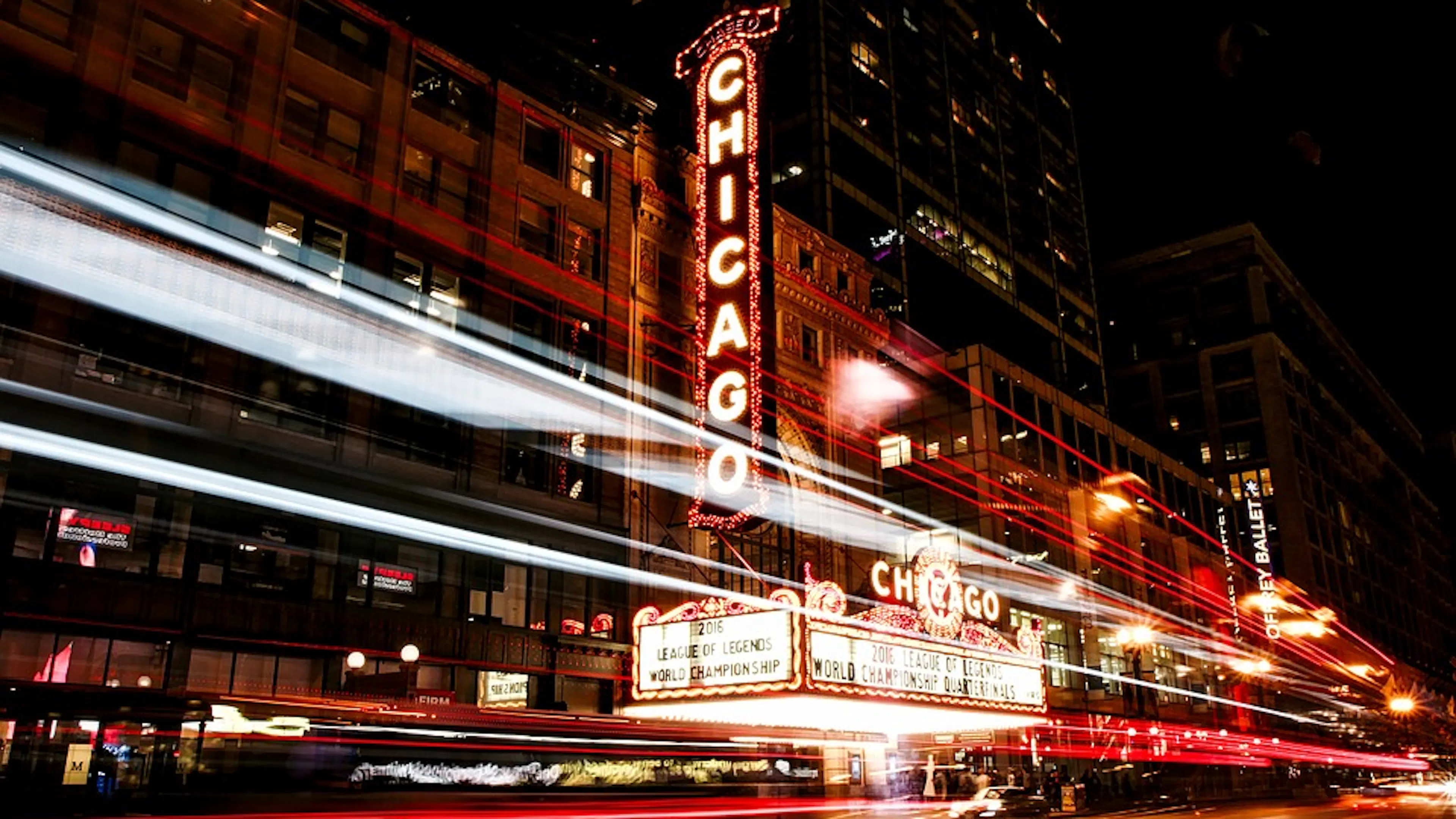 Street view of a movie theatre at night with the word Chicago lit up in bright lights 