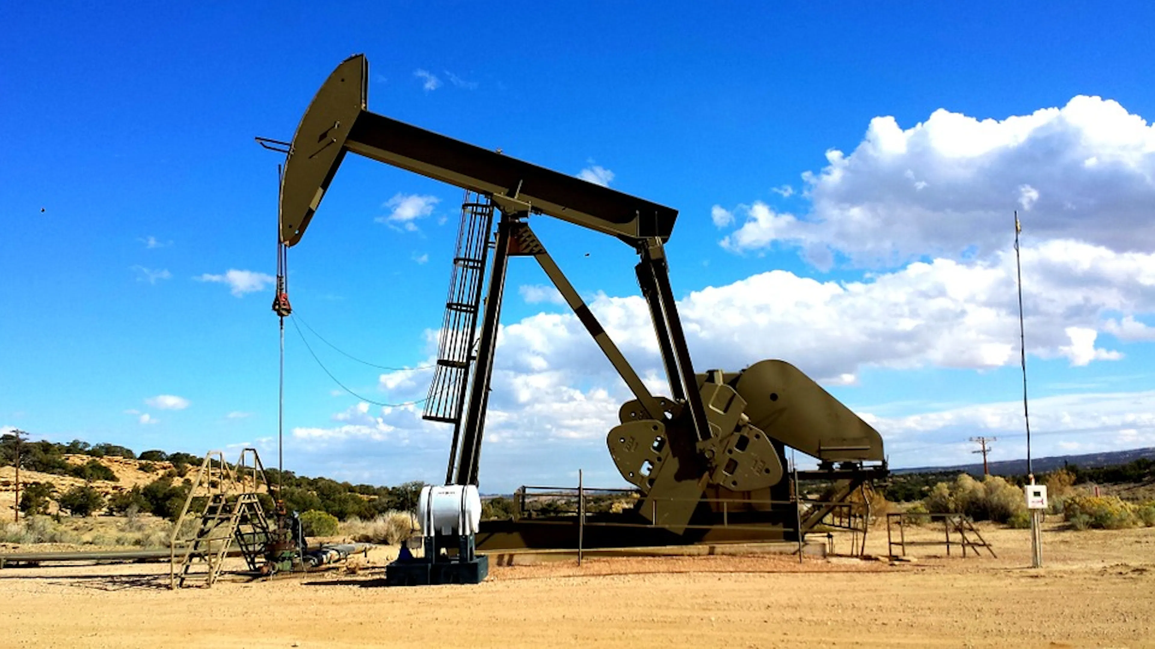 An oil drill in a sandy valley with a blue sky in the background