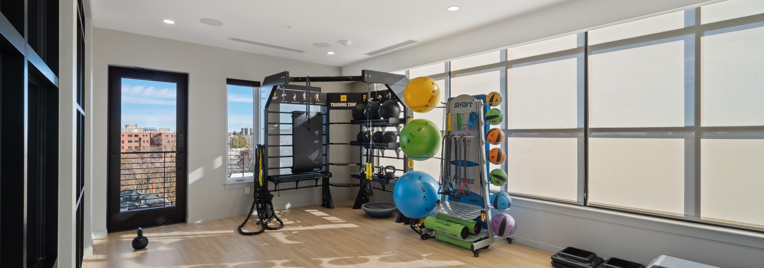 AMLI at Uptown yoga and training studio amenity with light flooring and wide open space featuring racks of equipment along the wall