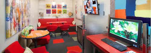 AMLI 300 media room with red couches and chairs, red and black carpet, orange tables, and computer desktops