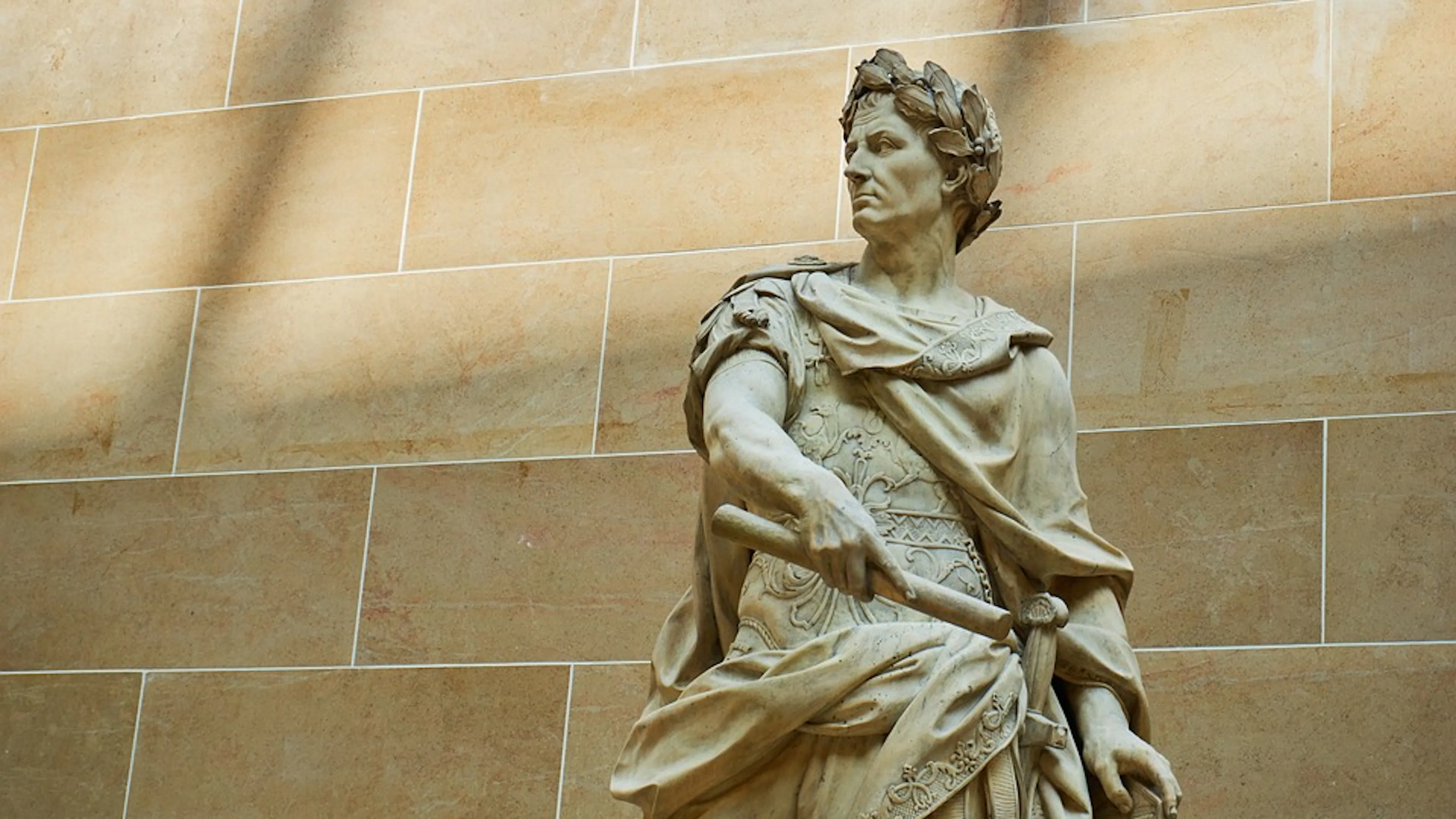 A statue of the Roman Emperor Julius Caesar with a laurel wreath on his head and a cloak over his shoulders