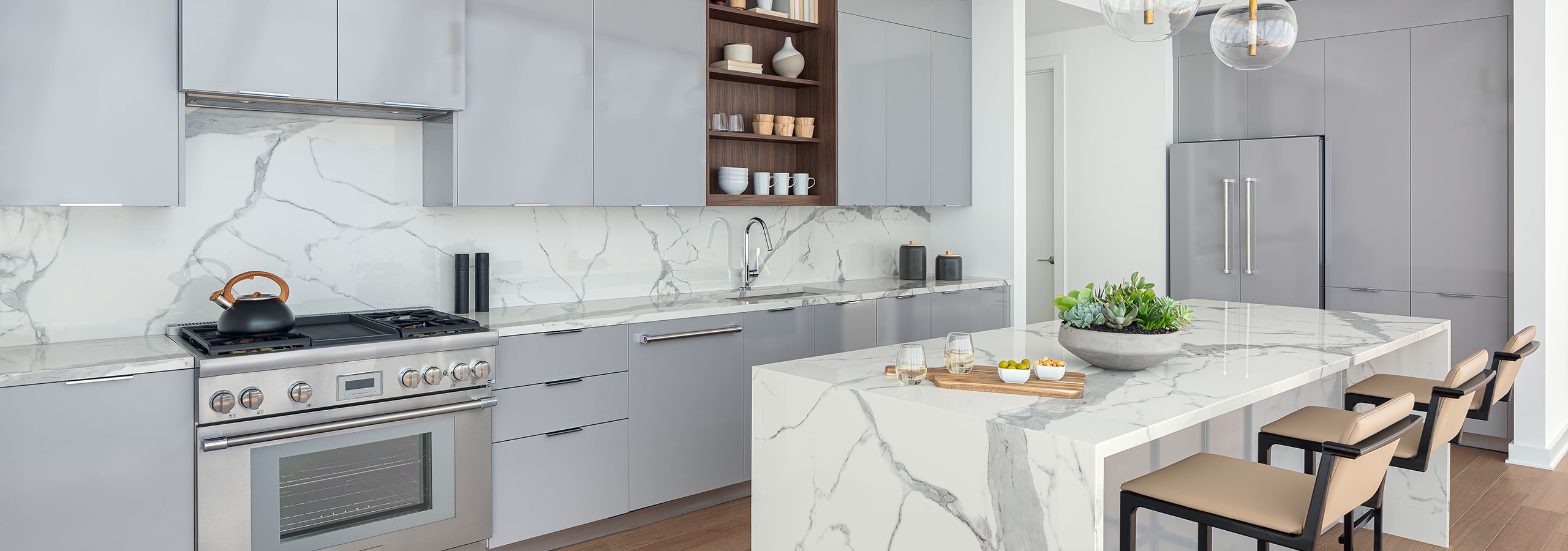 AMLI Fountain Place penthouse apartment kitchen with gray cabinets and white stone backslash and island and wood floors