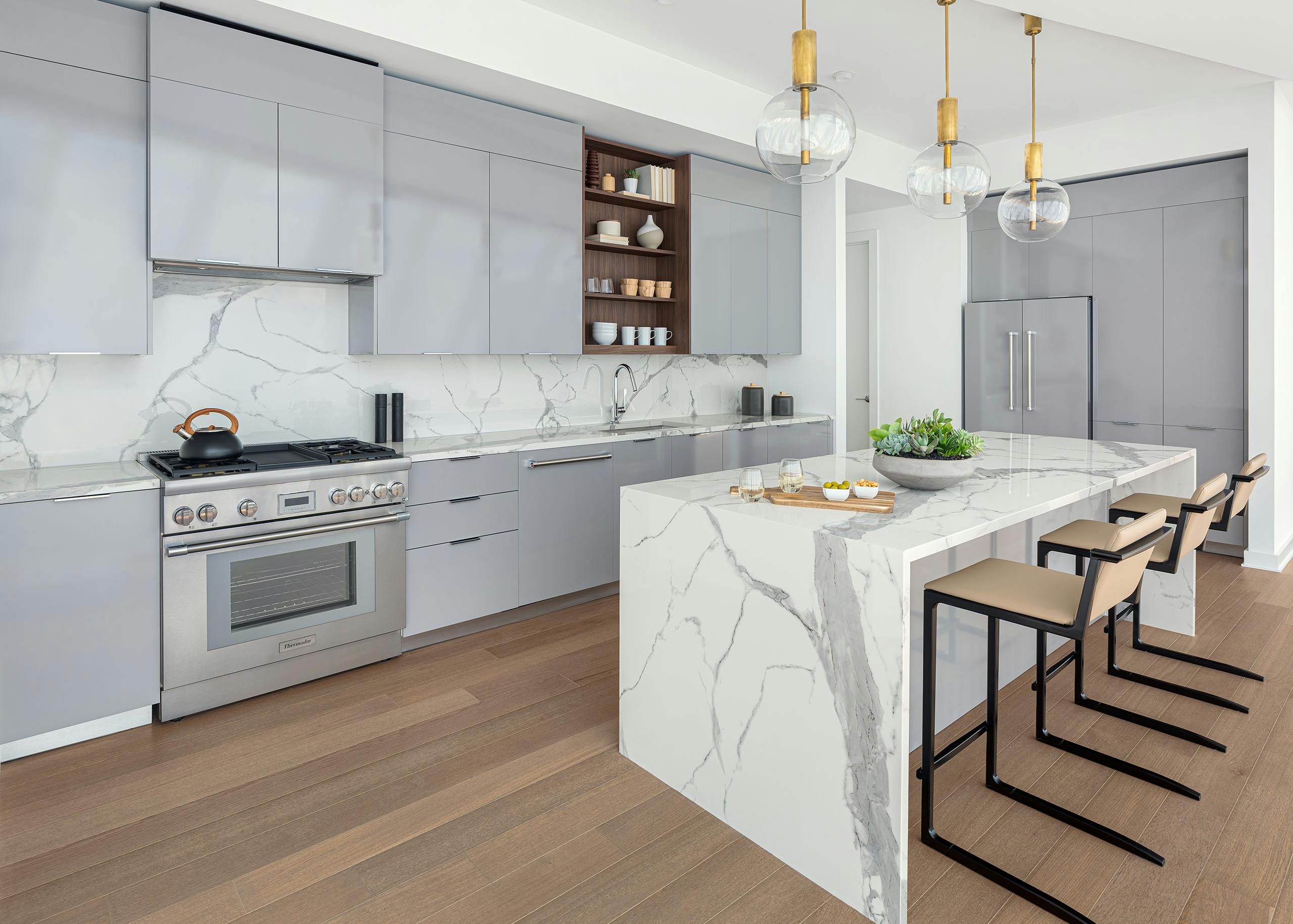 AMLI Fountain Place penthouse apartment kitchen with gray cabinets and white stone backslash and island and wood floors