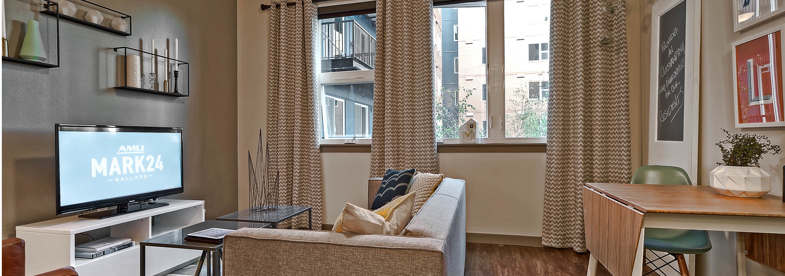 Interior view of living room at AMLI Mark24 apartment with large window grey walls with fun art on the walls