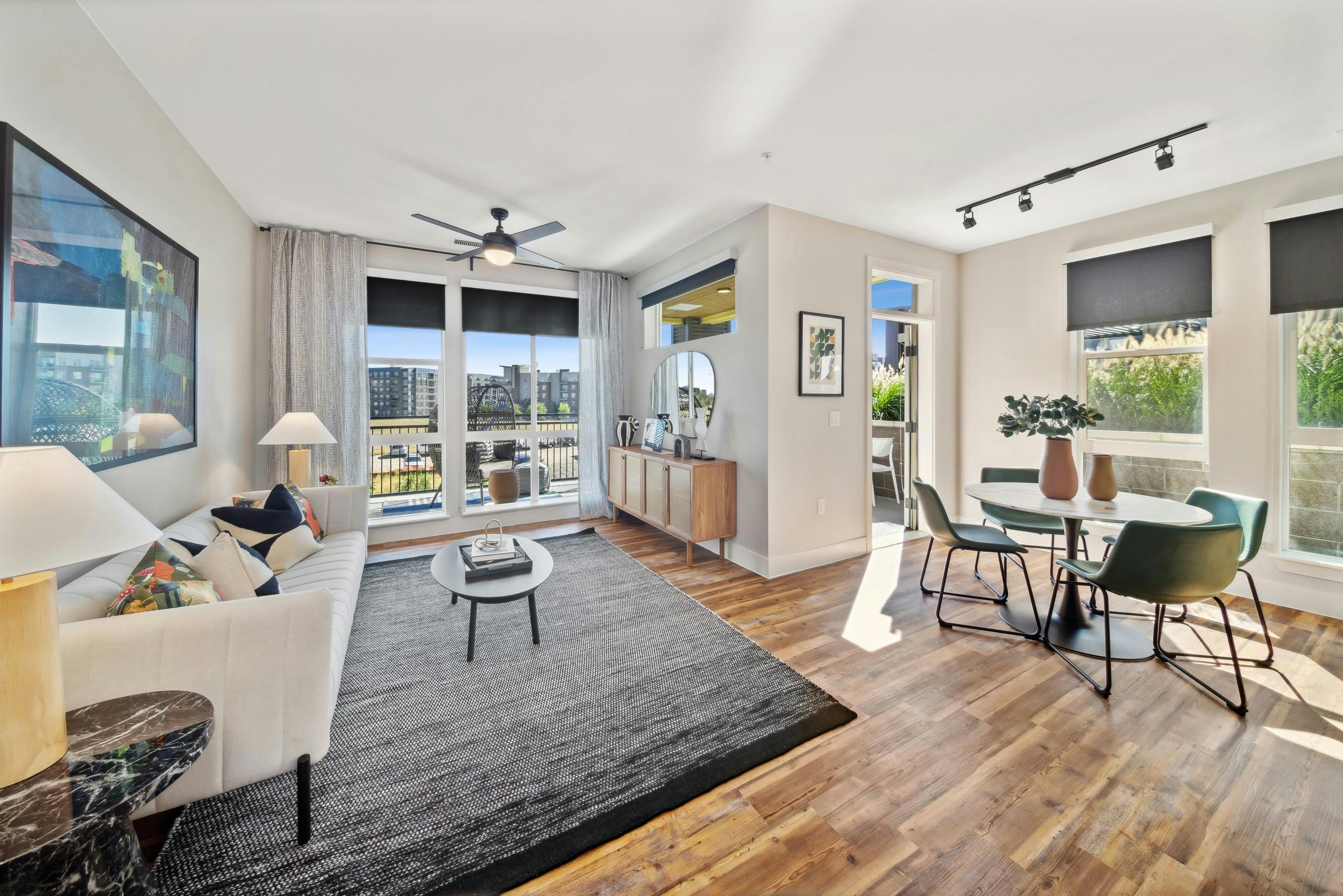 AMLI RiNo living room with white couch and grey rug and dining table and chairs on wood floors with balcony with city view