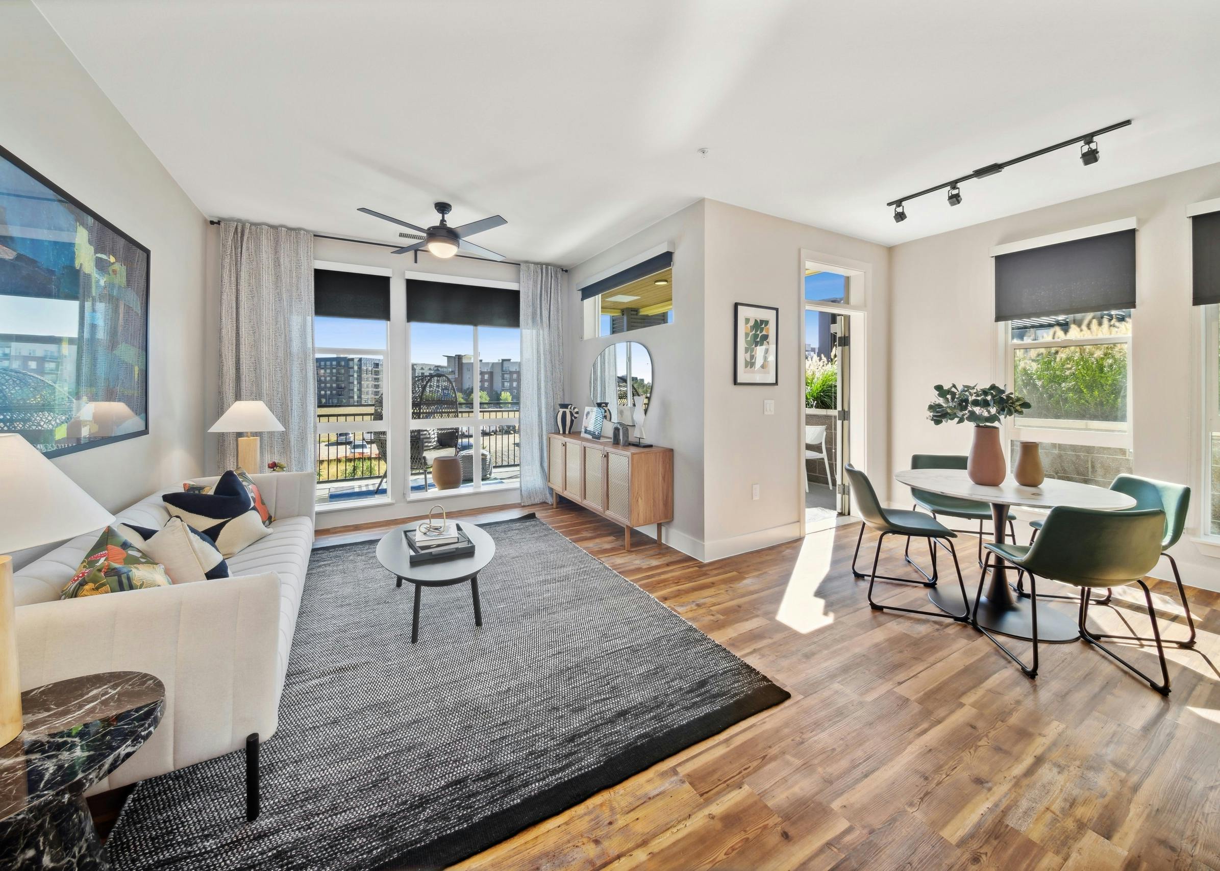 AMLI RiNo living room with white couch and grey rug and dining table and chairs on wood floors with balcony with city view