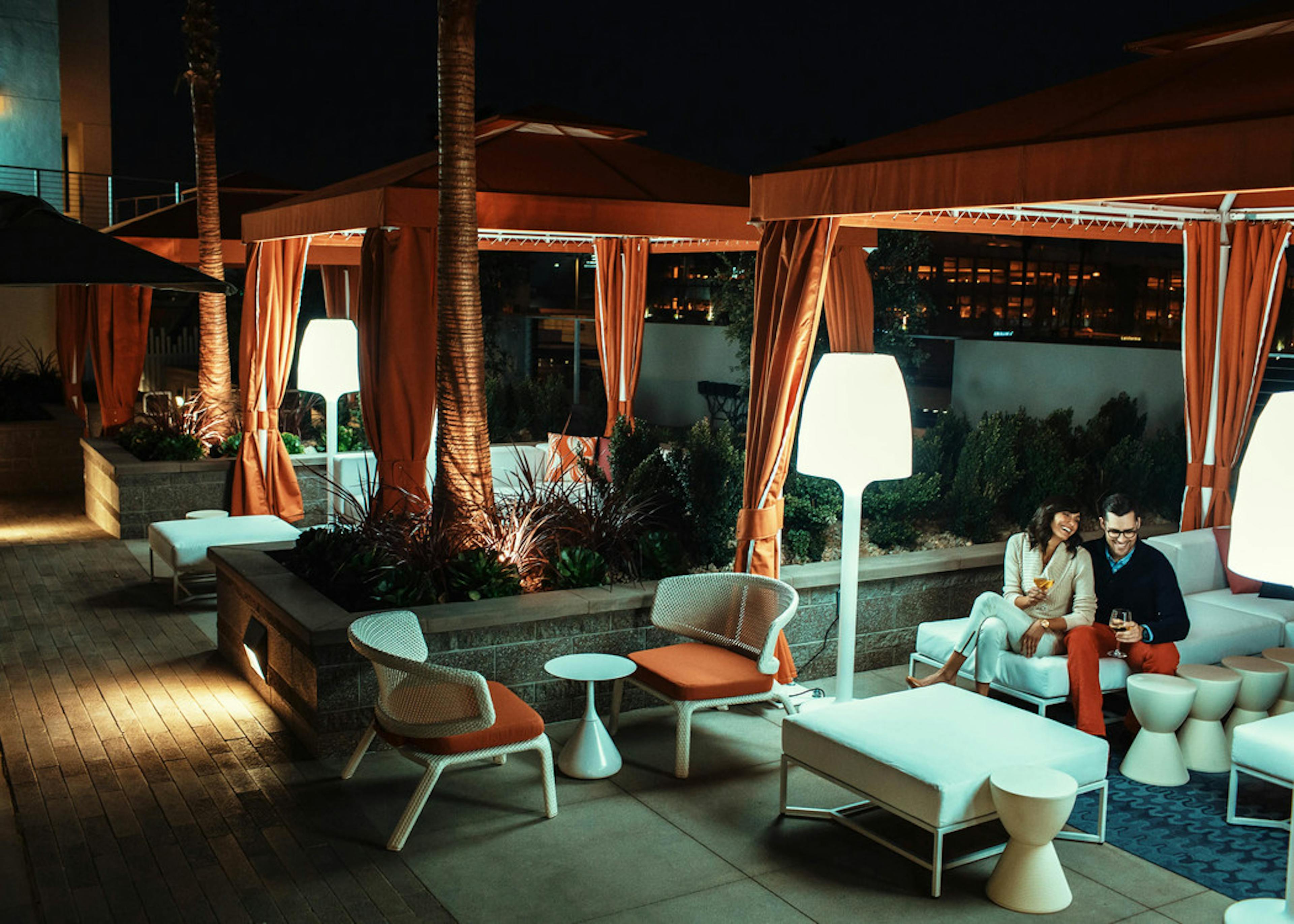 Nighttime view of AMLI Lex on Orange pool deck personal curtained cabanas with comfortable seating, patio lamps and a couple 
