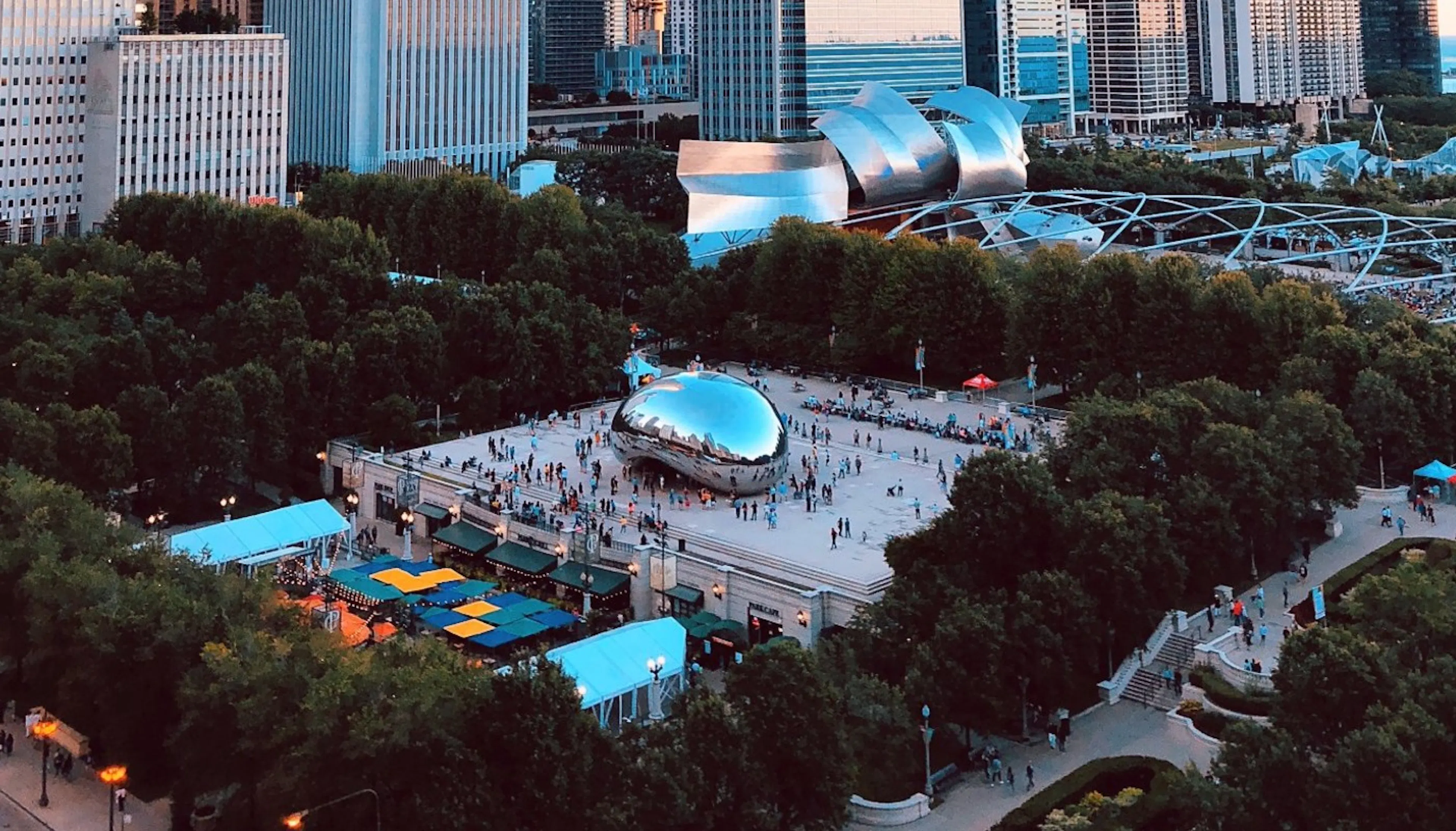 Aerial view of Millenium Park and Pritzker Pavilion with groups of people congregating at the Cloud Gate sculpture