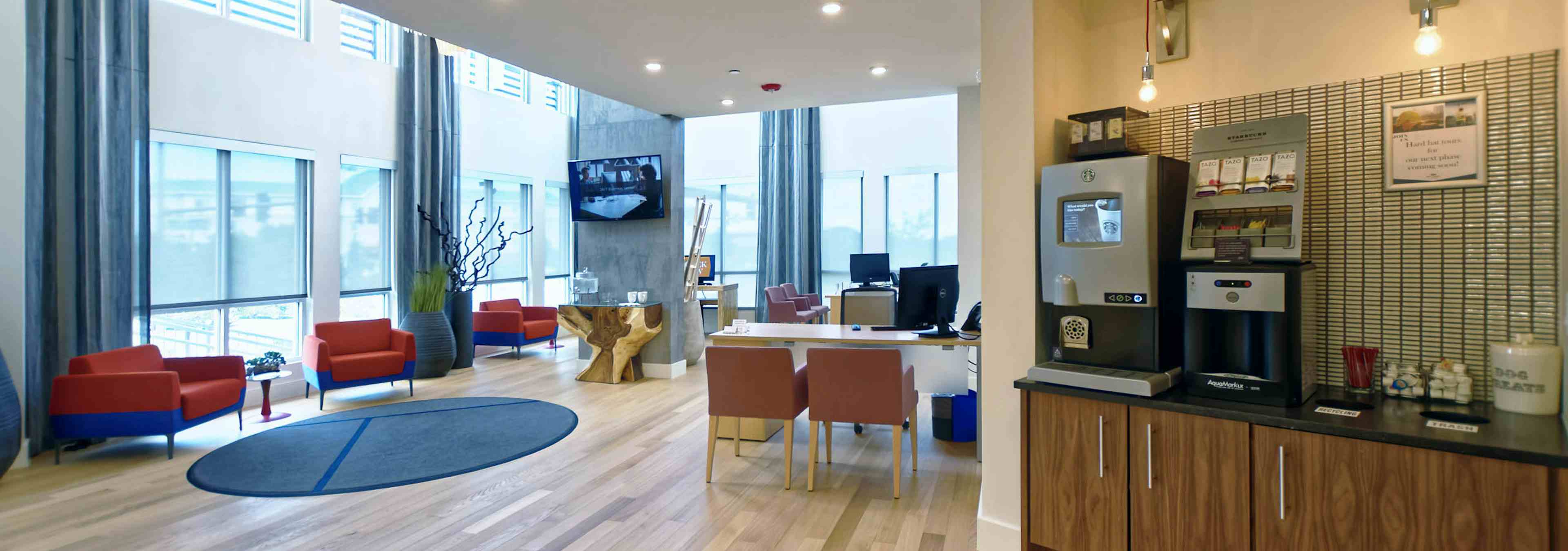 Leasing office at AMLI Dry Creek apartments with a coffee machine and desks and chairs with computers and view of front door