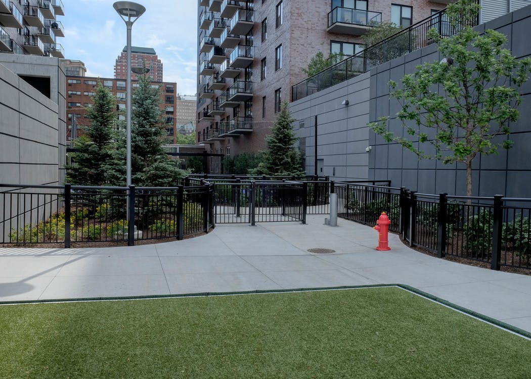 Exterior view of the gated dog run with artificial turf at the AMLI Lofts apartment community in the bright day time