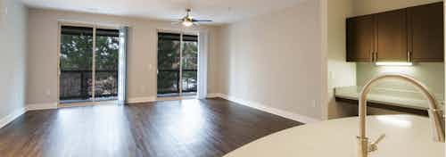 Interior view of redesigned kitchen and living room at AMLI Inverness apartments with hard wood floor and glass sliding door